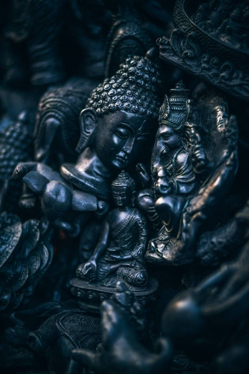 black buddha 桌布 壁紙 — 複雜深色金屬佛像與神像的特寫，帶有深藍色陰影和反光表面。