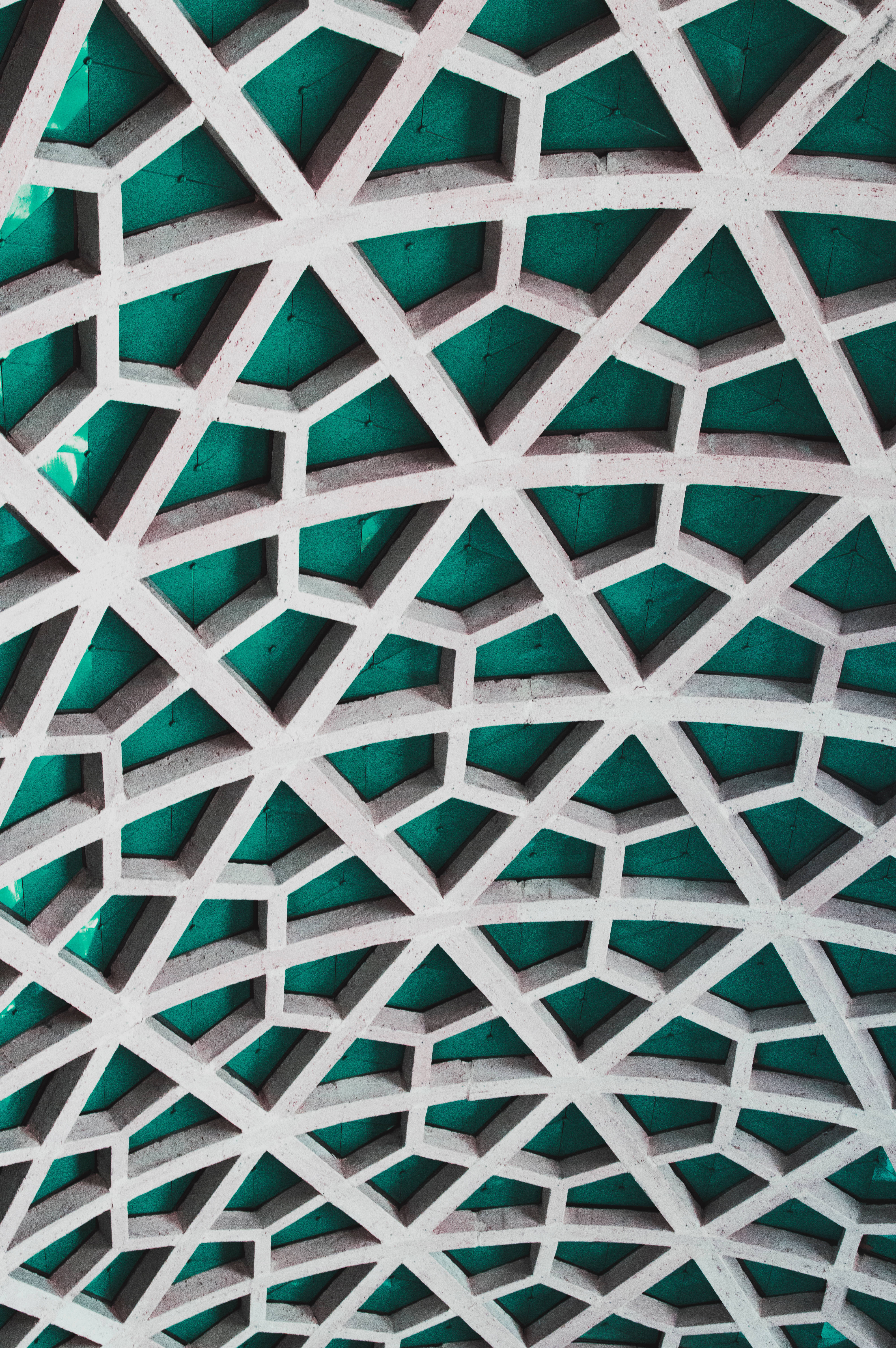 青色GIF 桌布 壁紙 — 複雜白色幾何格子結構的特寫，搭配深青色面板，營造出大膽的建築圖案。
