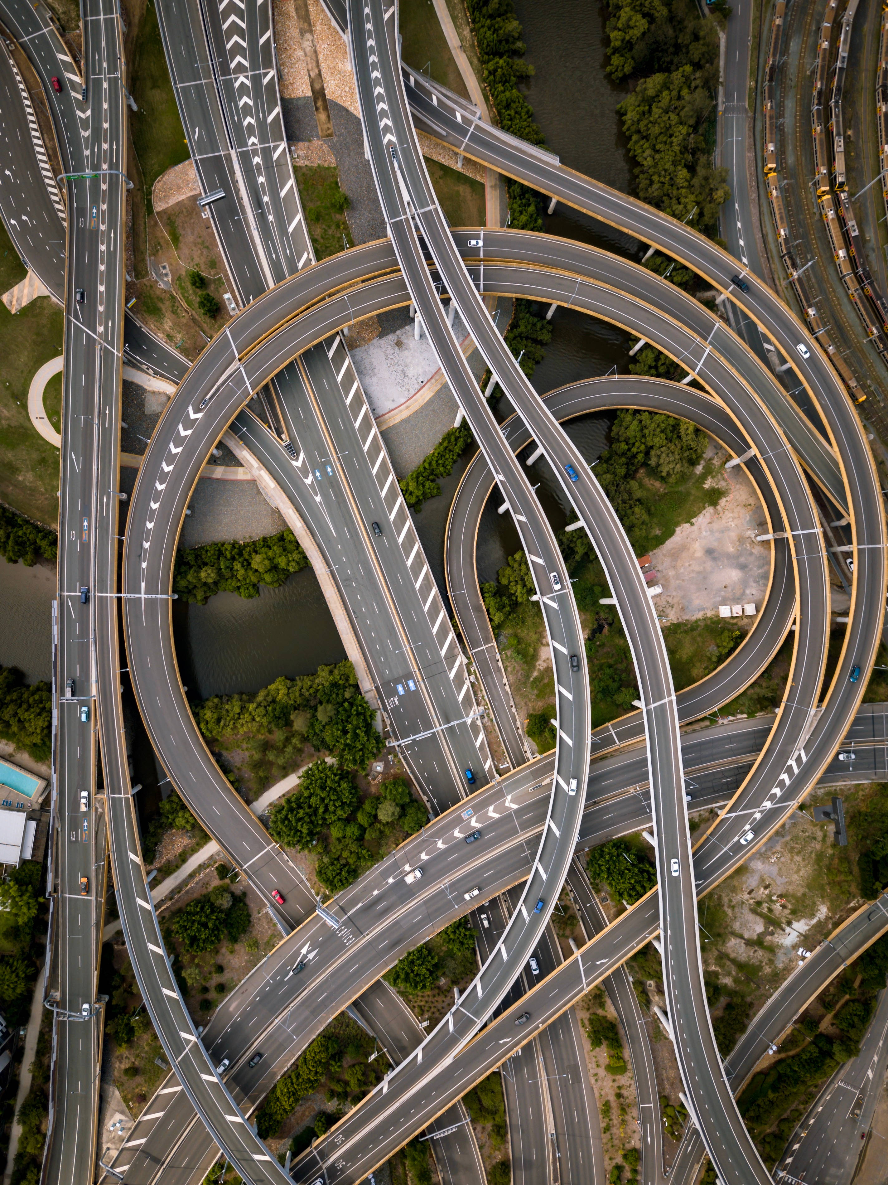 Road 桌布 壁紙 — 複雜高速公路交匯處的空中景觀，彎曲的道路和稀疏的交通，周圍環繞著綠化。