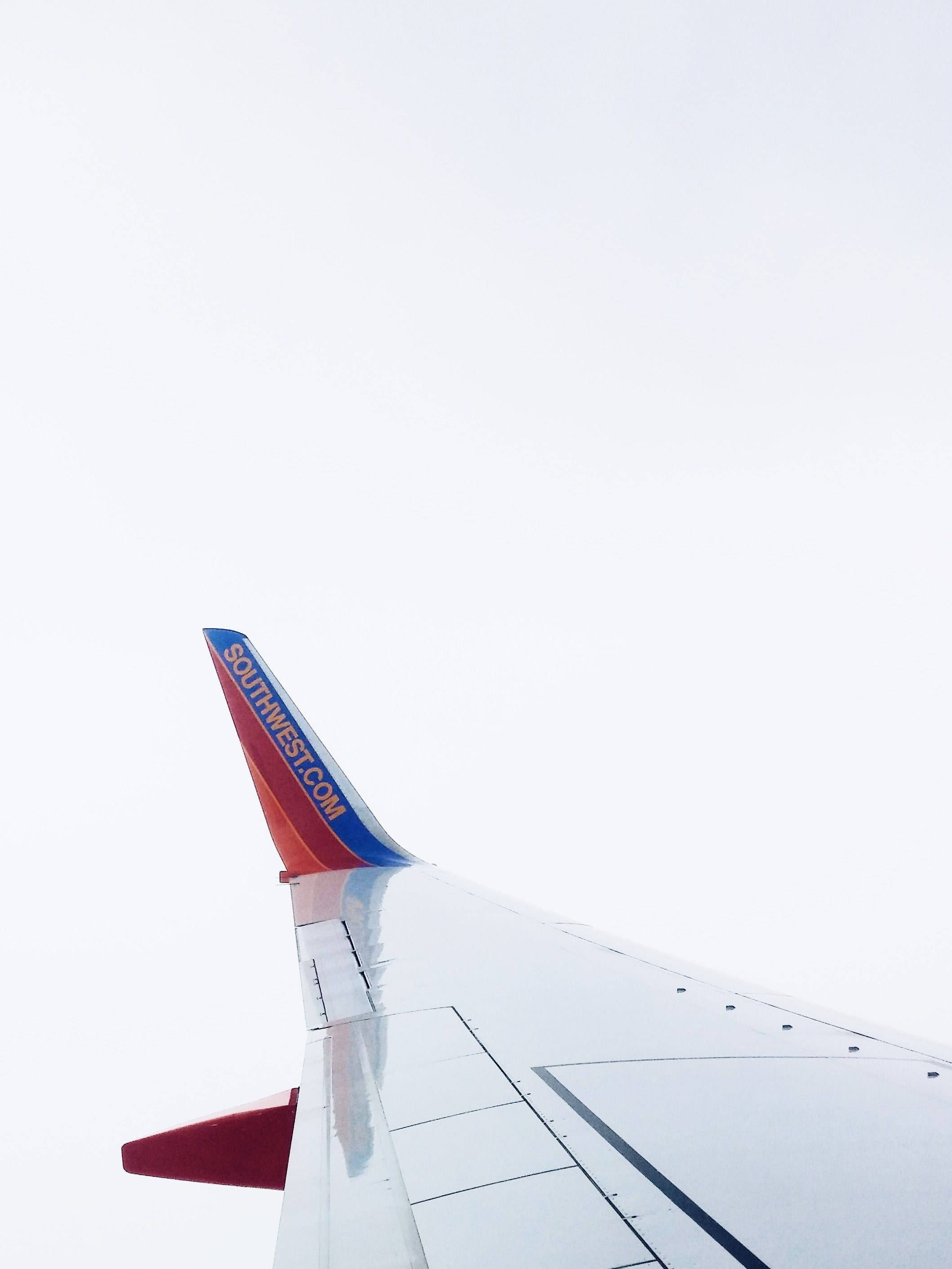 飛機 桌布 壁紙 — 西南航空飛機機翼在明亮多雲天空下的特寫視圖。