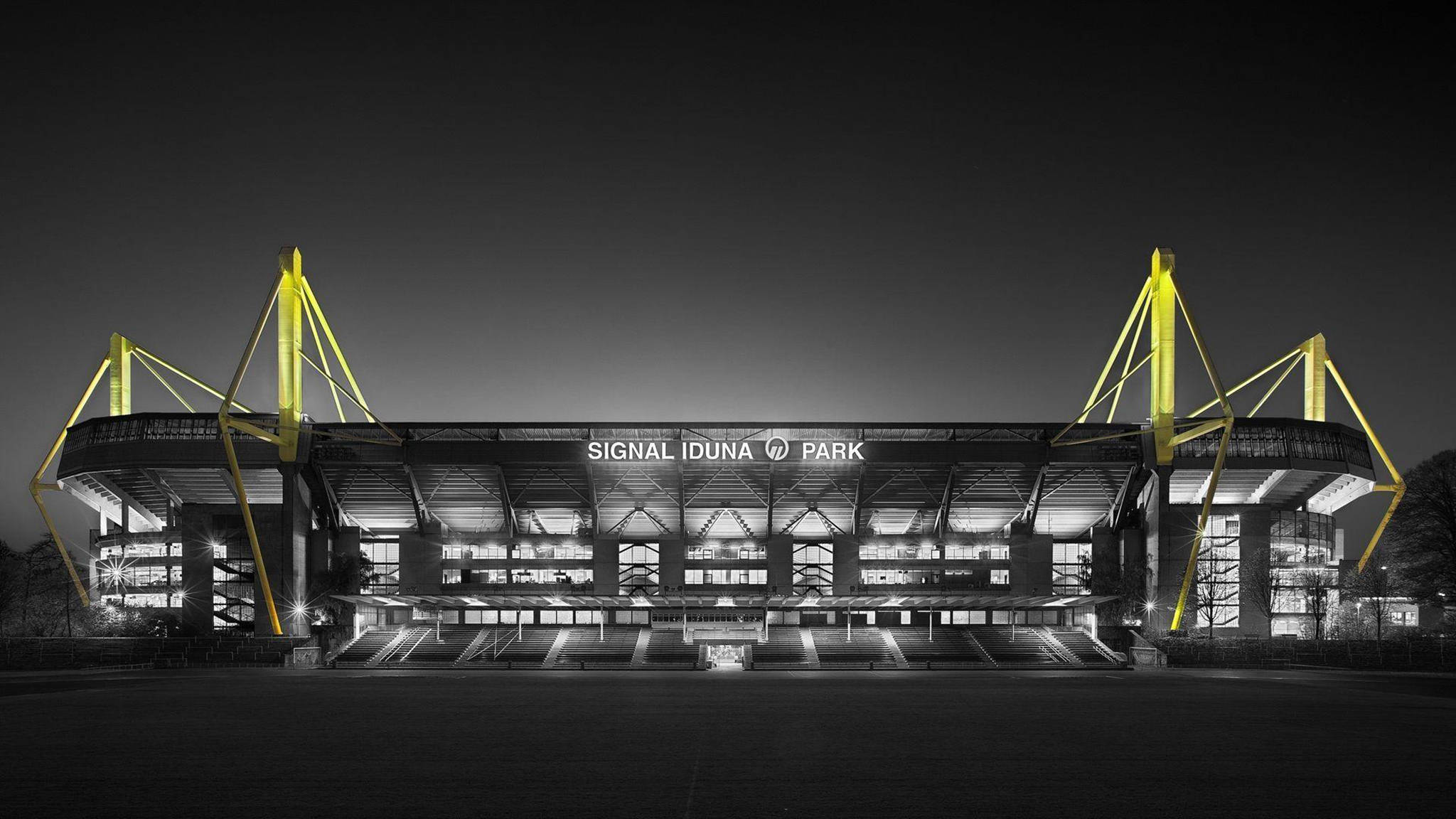Stadium 桌布 壁紙 — 西格納伊度納公園球場在夜晚亮起，醒目的黃色結構樑柱映襯著黑暗的天空。