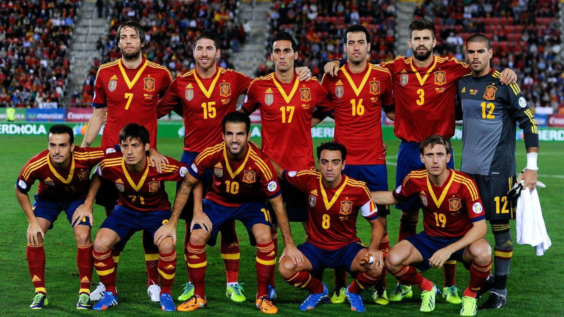 Spain 桌布 壁紙 — 西班牙國家足球隊身穿紅色球衣在球場上擺姿勢，背景有球迷。