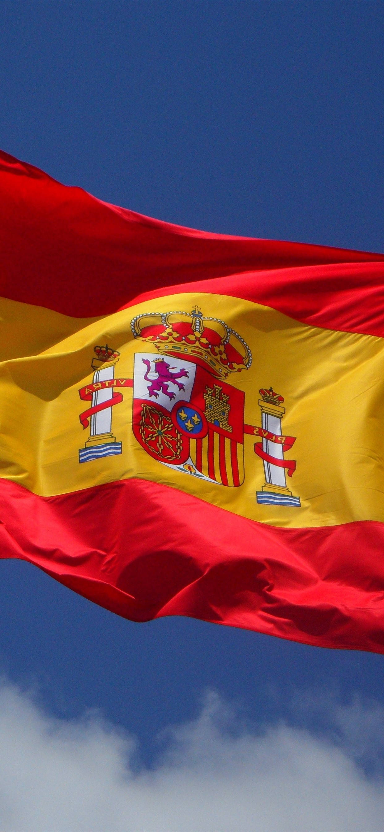 Spain Flag 桌布 壁紙 — 西班牙國旗在晴朗藍天與零星白雲中動態飄揚。