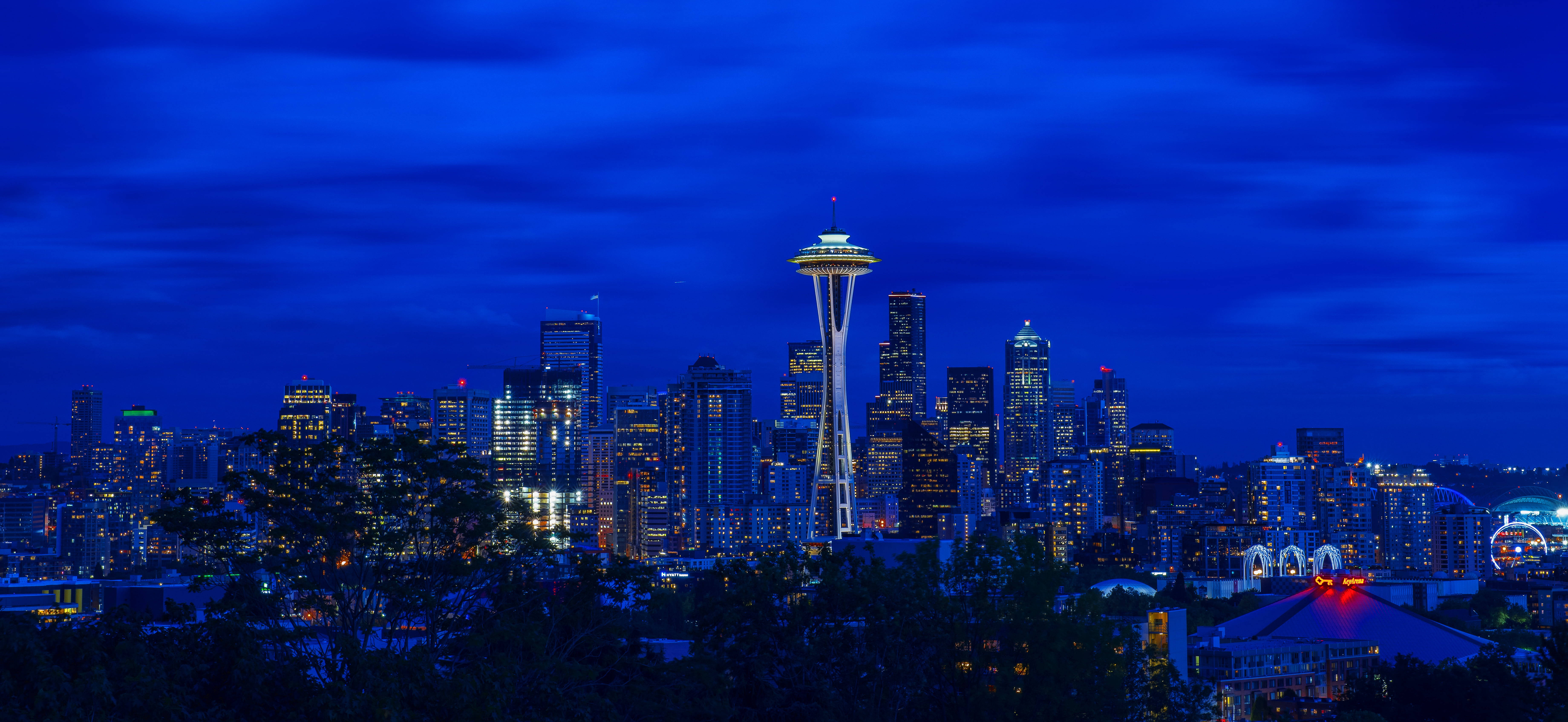 Washington 桌布 壁紙 — 西雅圖夜景，太空針塔在深藍色天空下閃耀，城市燈光在下方閃爍。