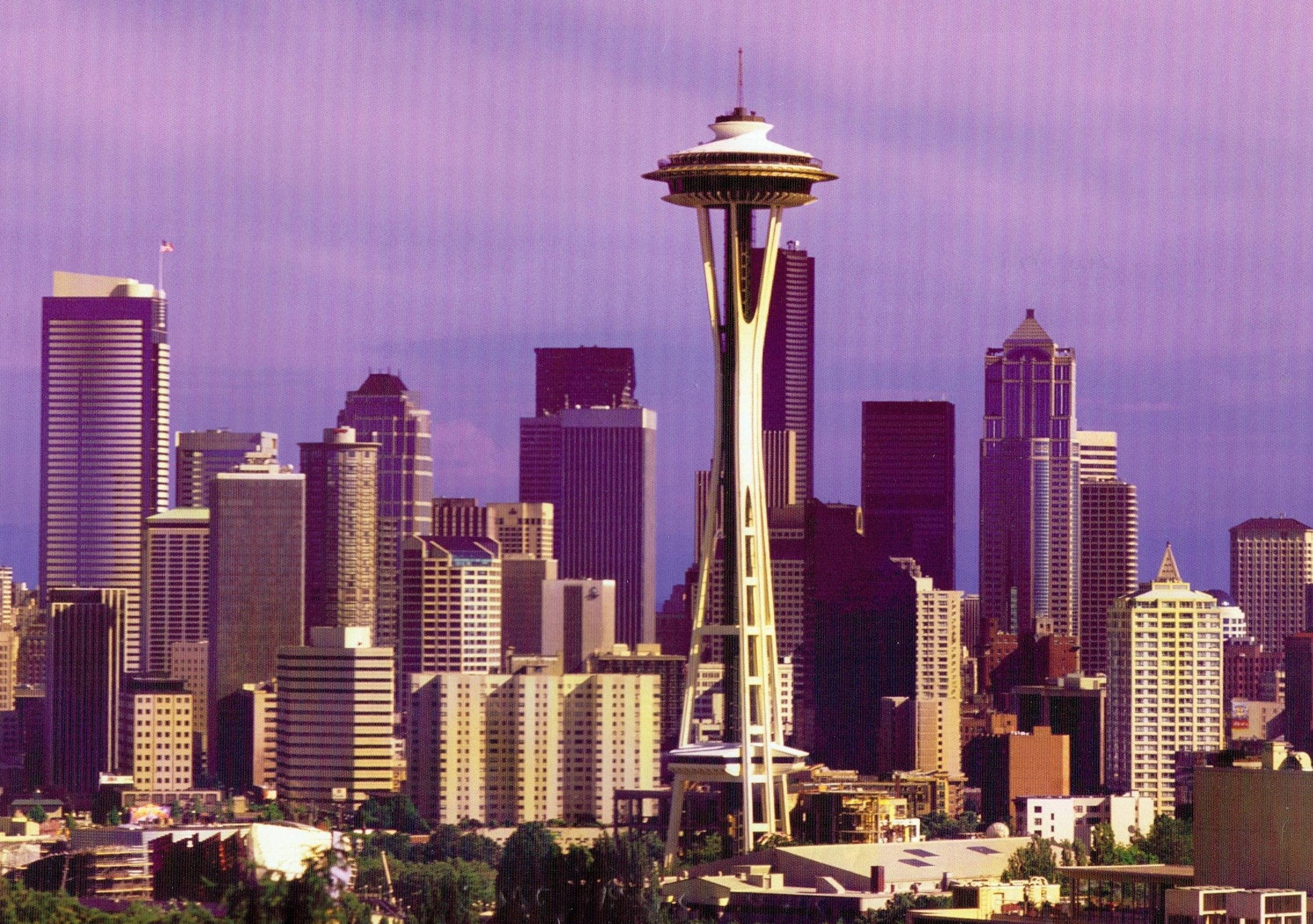 Space Needle 桌布 壁紙 — 西雅圖天際線以太空針塔為主角，紫色天空下高樓大廈林立，下方綠樹成蔭。