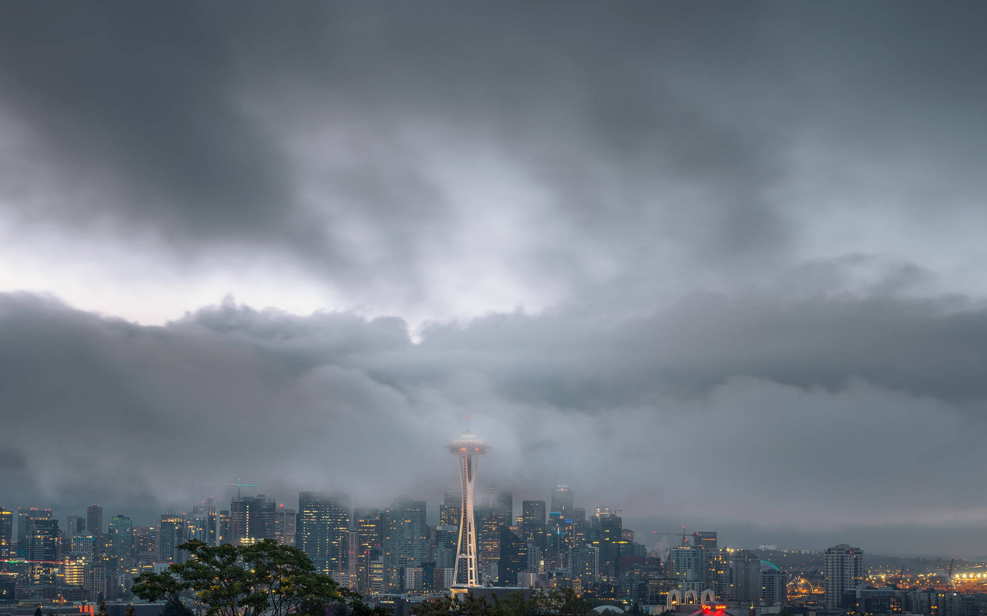 Space Needle 桌布 壁紙 — 西雅圖天際線刺穿戲劇性的暴風雲，太空針塔在陰鬱的暮色中閃耀。