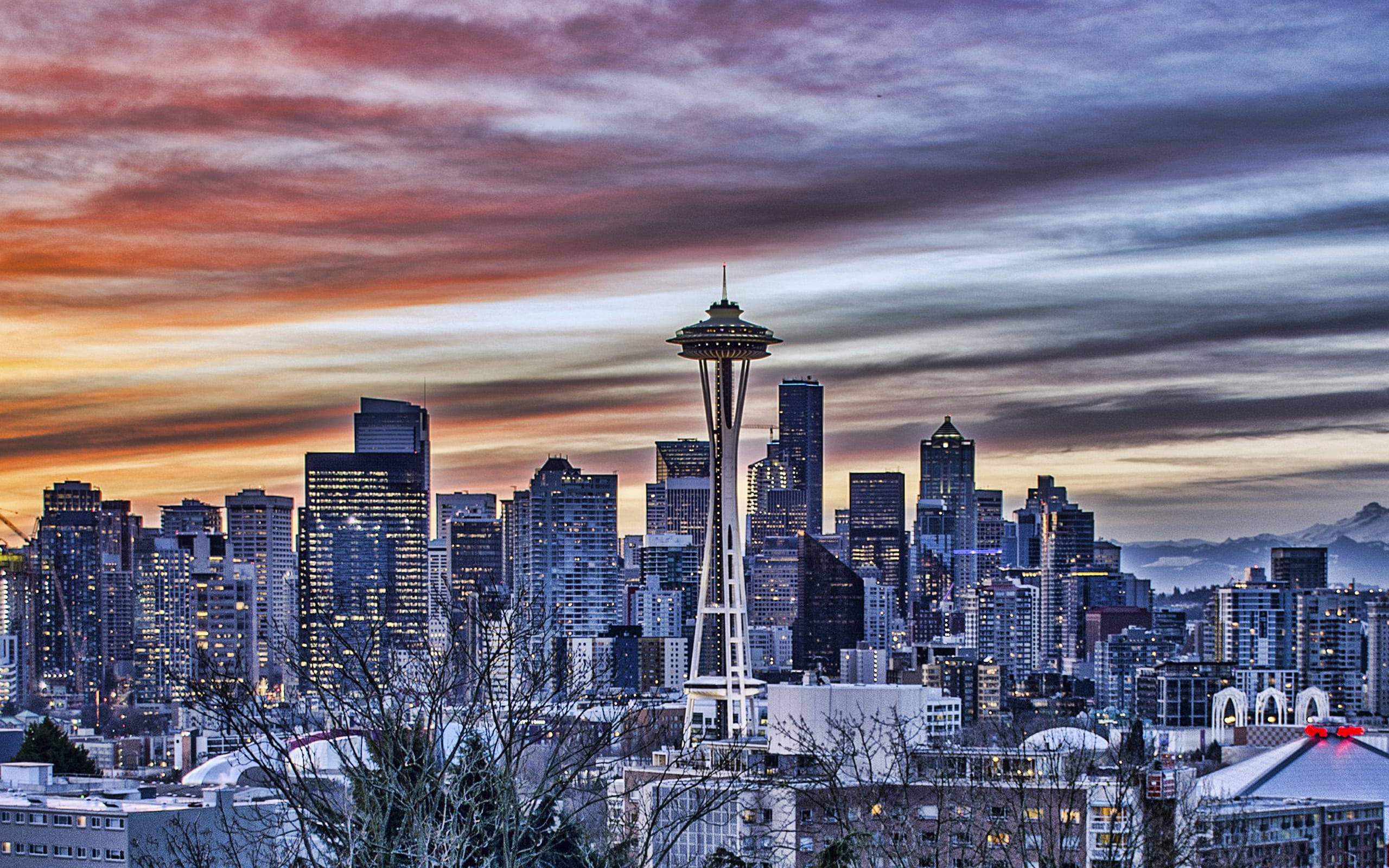 Space Needle 桌布 壁紙 — 西雅圖天際線在日落時分，太空針塔在火橙色和紫色雲彩中閃耀。