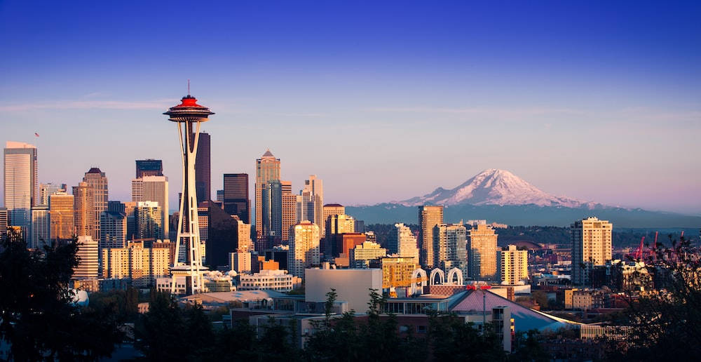 Seattle Skyline 桌布 壁紙 — 西雅圖天際線在日落時分，背景有太空針塔和積雪的雷尼爾山。