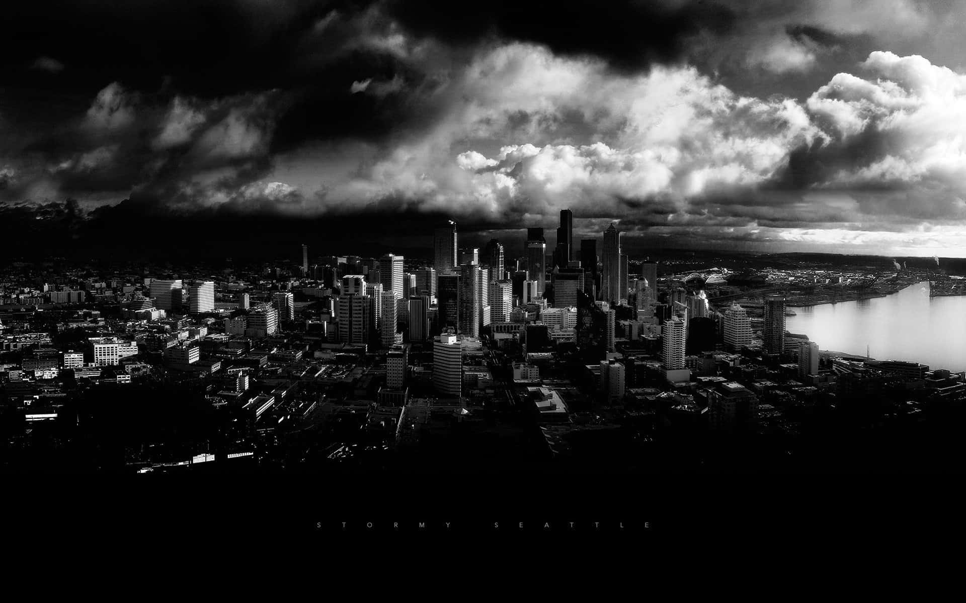 Buildings 桌布 壁紙 — 西雅圖天際線在暴風雨天空下的戲劇性黑白空拍圖，烏雲籠罩城市和水面。