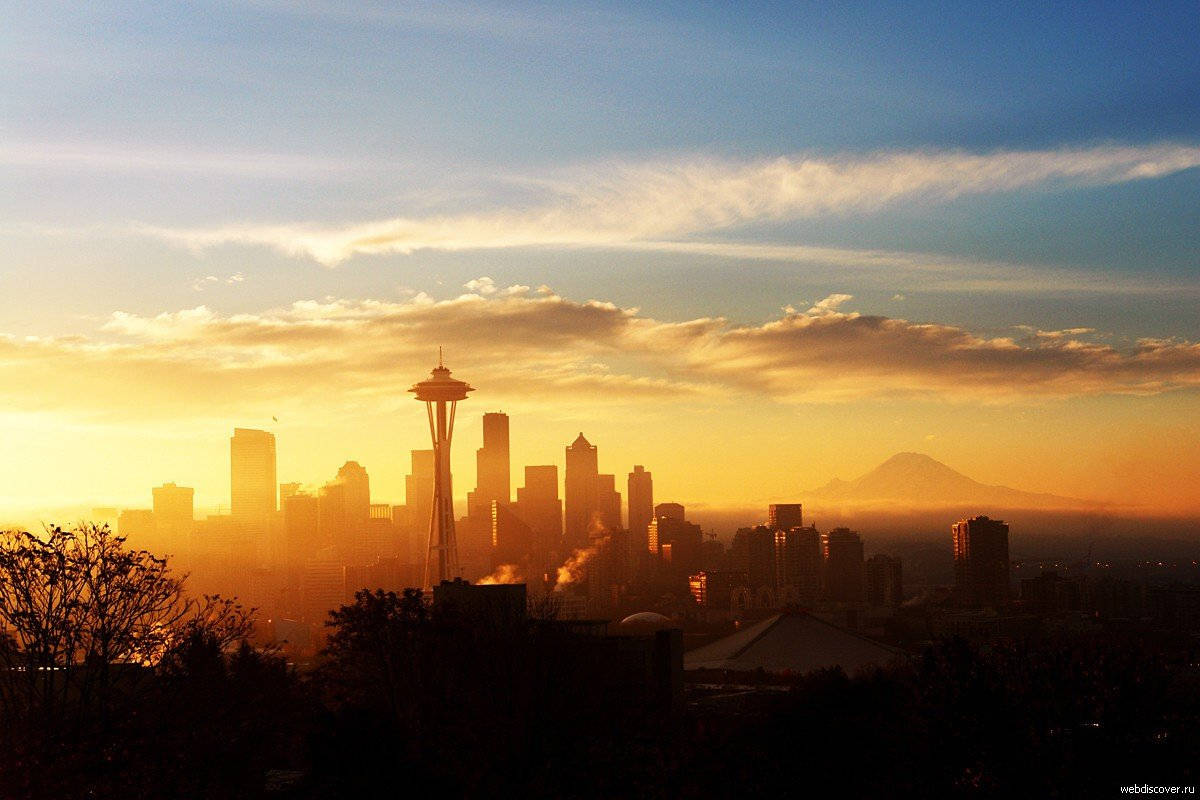 Seattle Skyline 桌布 壁紙 — 西雅圖天際線在金色日落時分，太空針塔和雷尼爾山在溫暖的雲層中形成剪影。