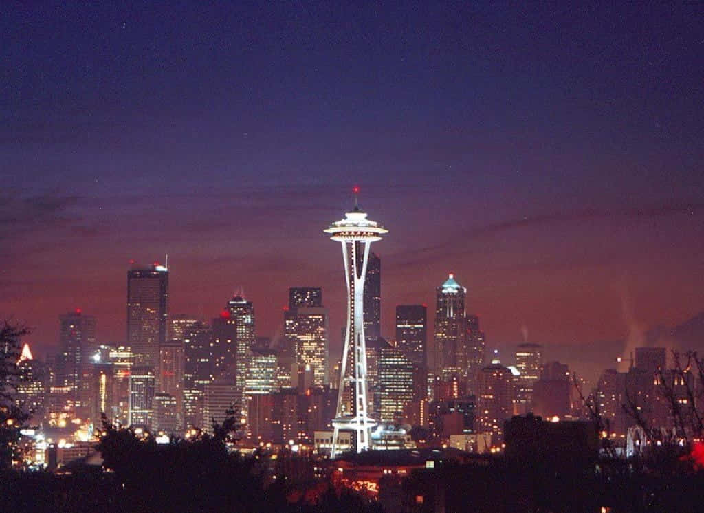 Seattle At Night 桌布 壁紙 — 西雅圖天際線在黃昏時分，太空針塔在深紫色和橙色的天空中閃耀。