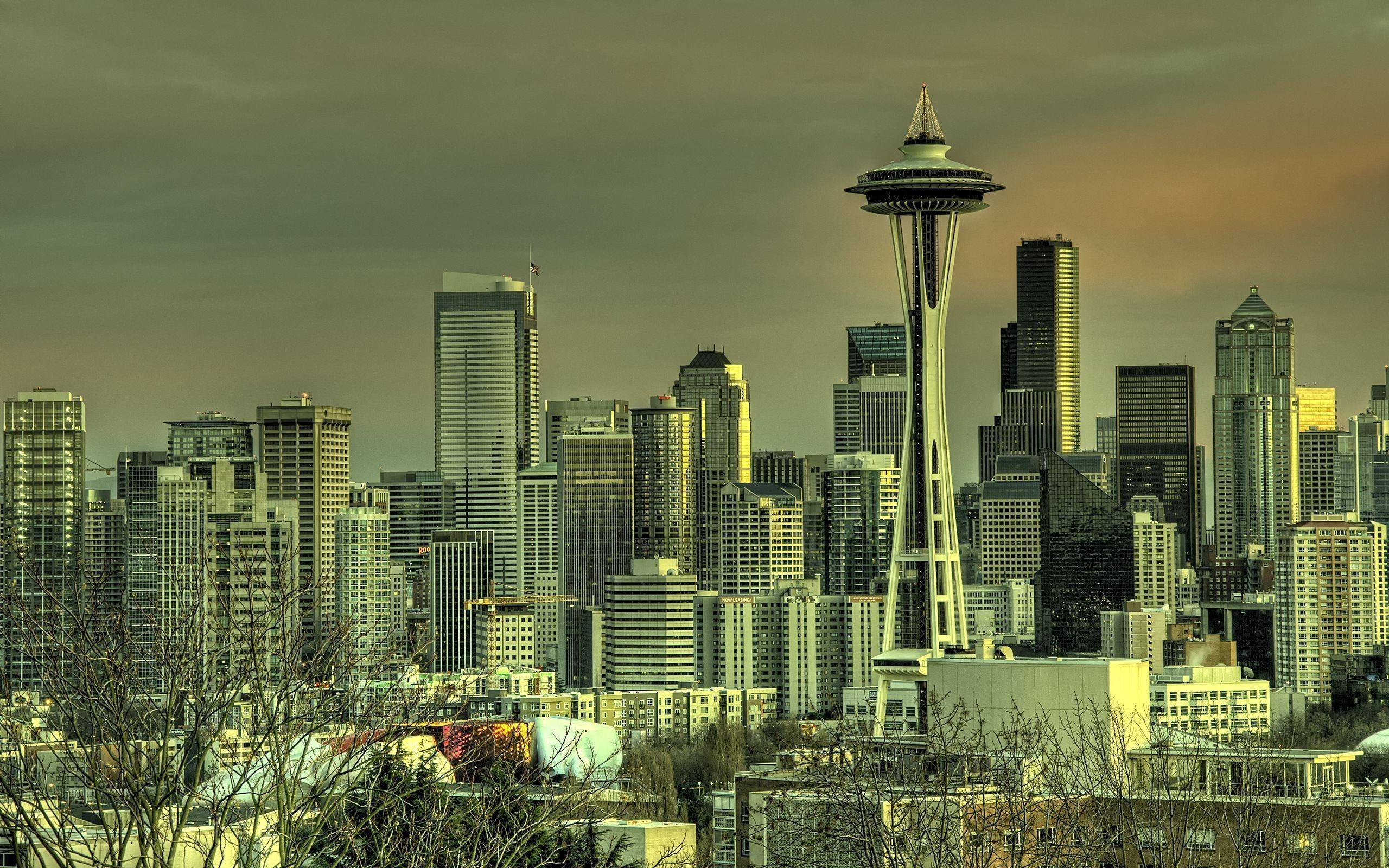 Space Needle 桌布 壁紙 — 西雅圖天際線在黃昏時分，太空針塔聳立在玻璃摩天大樓之上，溫暖的金色天空。