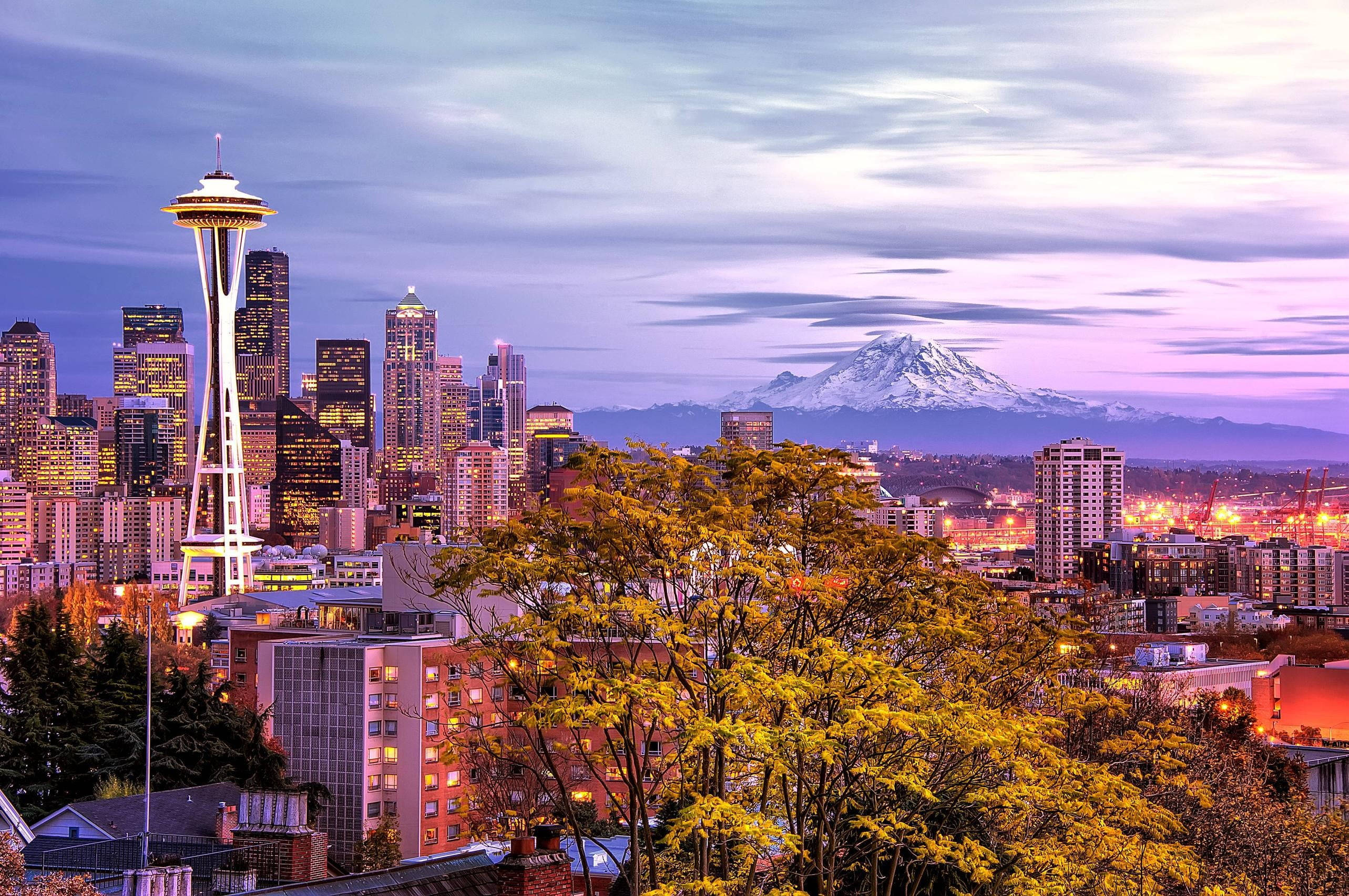 Washington 桌布 壁紙 — 西雅圖天際線在黃昏時分，太空針塔亮起，遠處積雪的雷尼爾山閃耀著光芒。