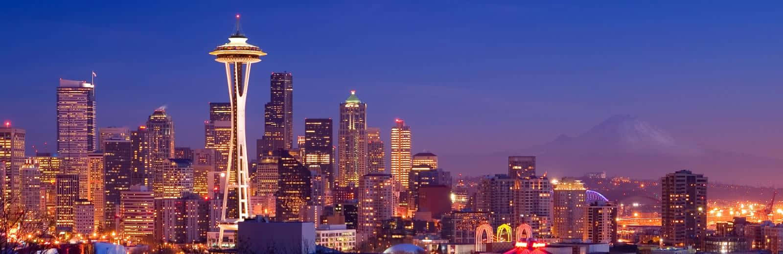 Washington 桌布 壁紙 — 西雅圖天際線在黃昏時分，太空針塔亮起燈光，遠處有積雪的雷尼爾山。