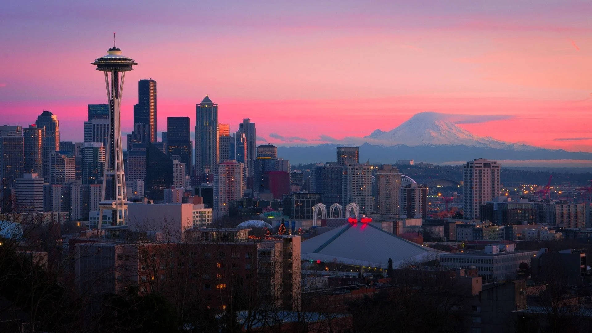 Seattle Skyline 桌布 壁紙 — 西雅圖天際線在黃昏時分，太空針塔和積雪的雷尼爾山在粉紅色和紫色的天空下閃耀。
