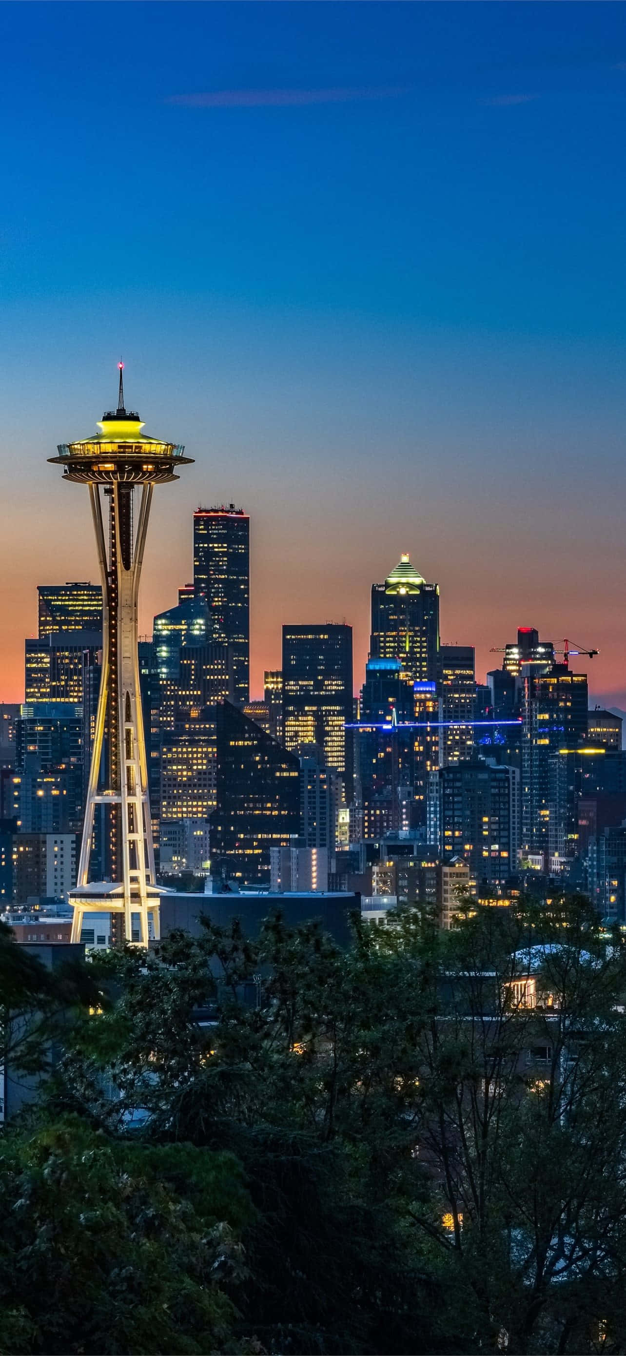 Seattle At Night 桌布 壁紙 — 西雅圖天際線在黃昏時分，太空針塔在漸變的藍色和橙色天空中亮起。
