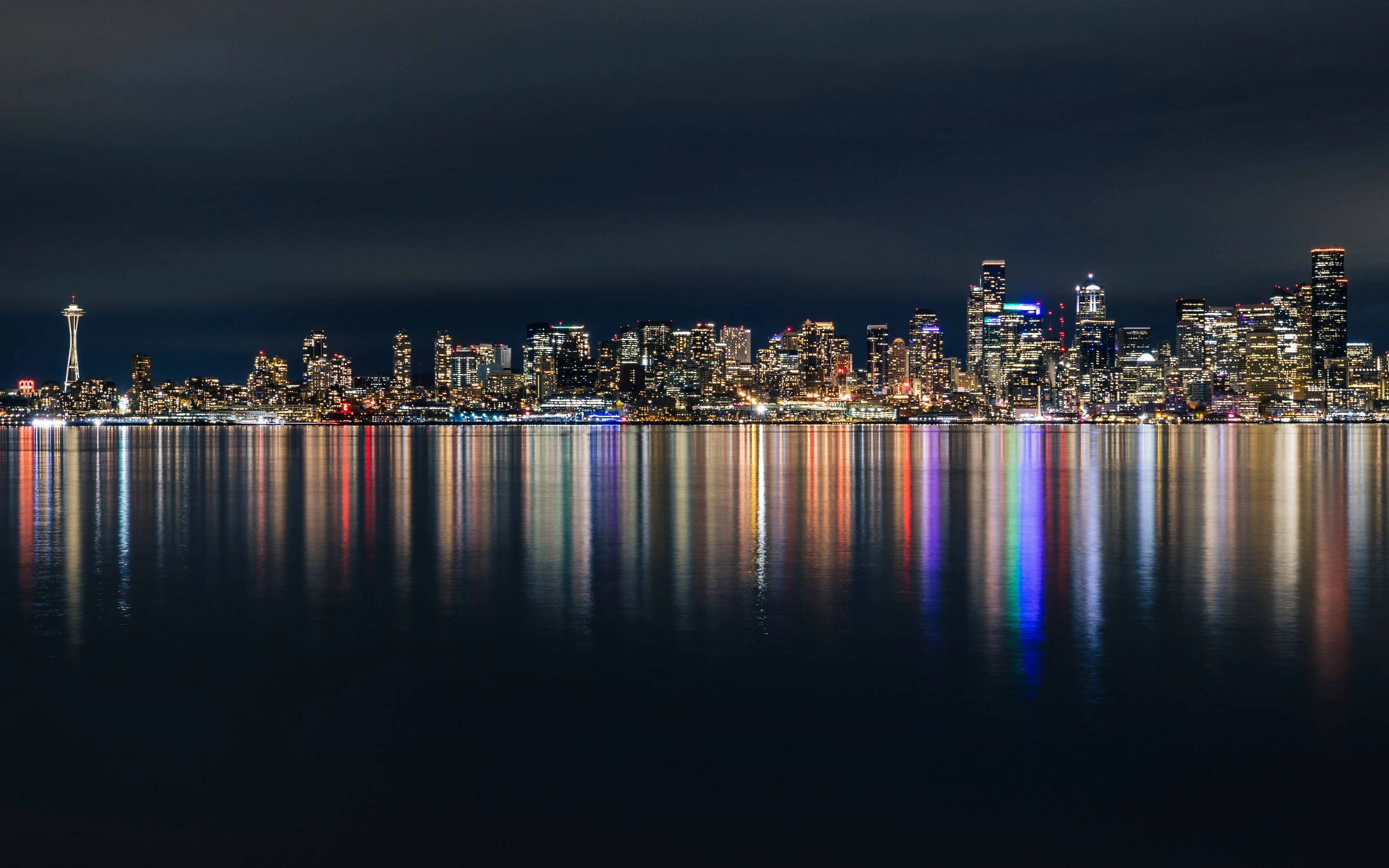 Seattle Skyline 桌布 壁紙 — 西雅圖天際線夜景，璀璨的城市燈光完美倒映在黑暗天空下的平靜水面上。