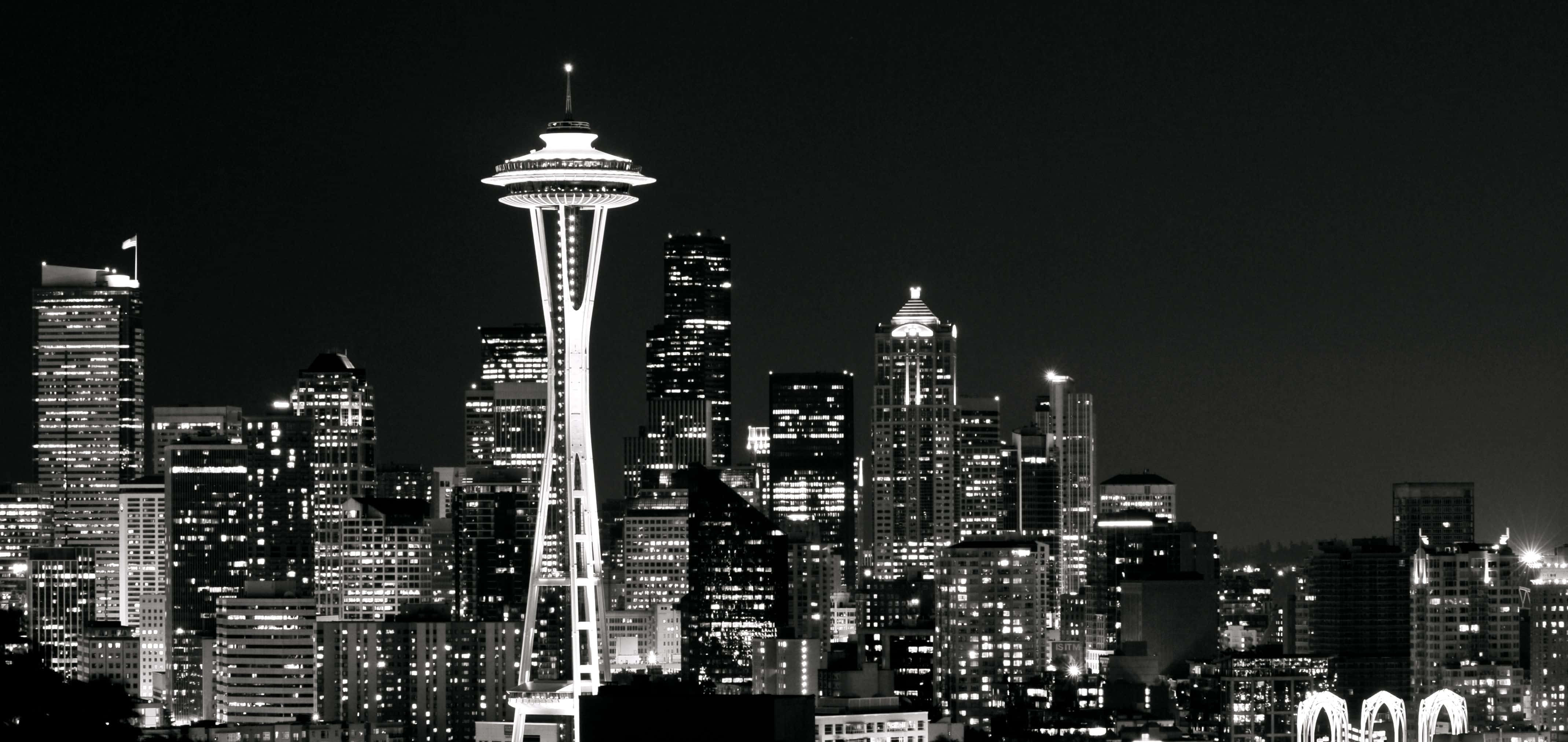 Seattle Black And White 桌布 壁紙 — 西雅圖天際線的醒目黑白夜景，以發光的太空針塔和閃爍的摩天大樓為主導。
