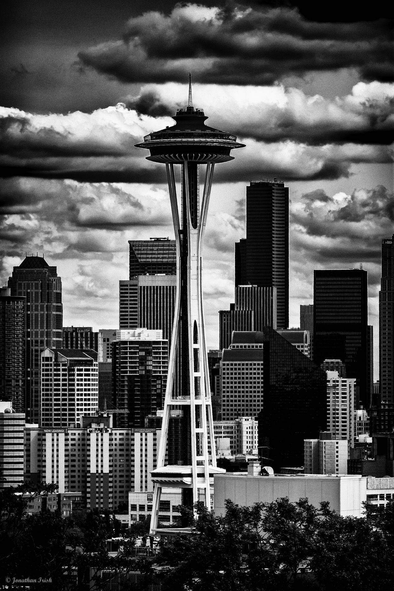 Seattle 桌布 壁紙 — 西雅圖太空針塔在戲劇性的雲層下聳立於密集城市天際線之上的單色景觀。