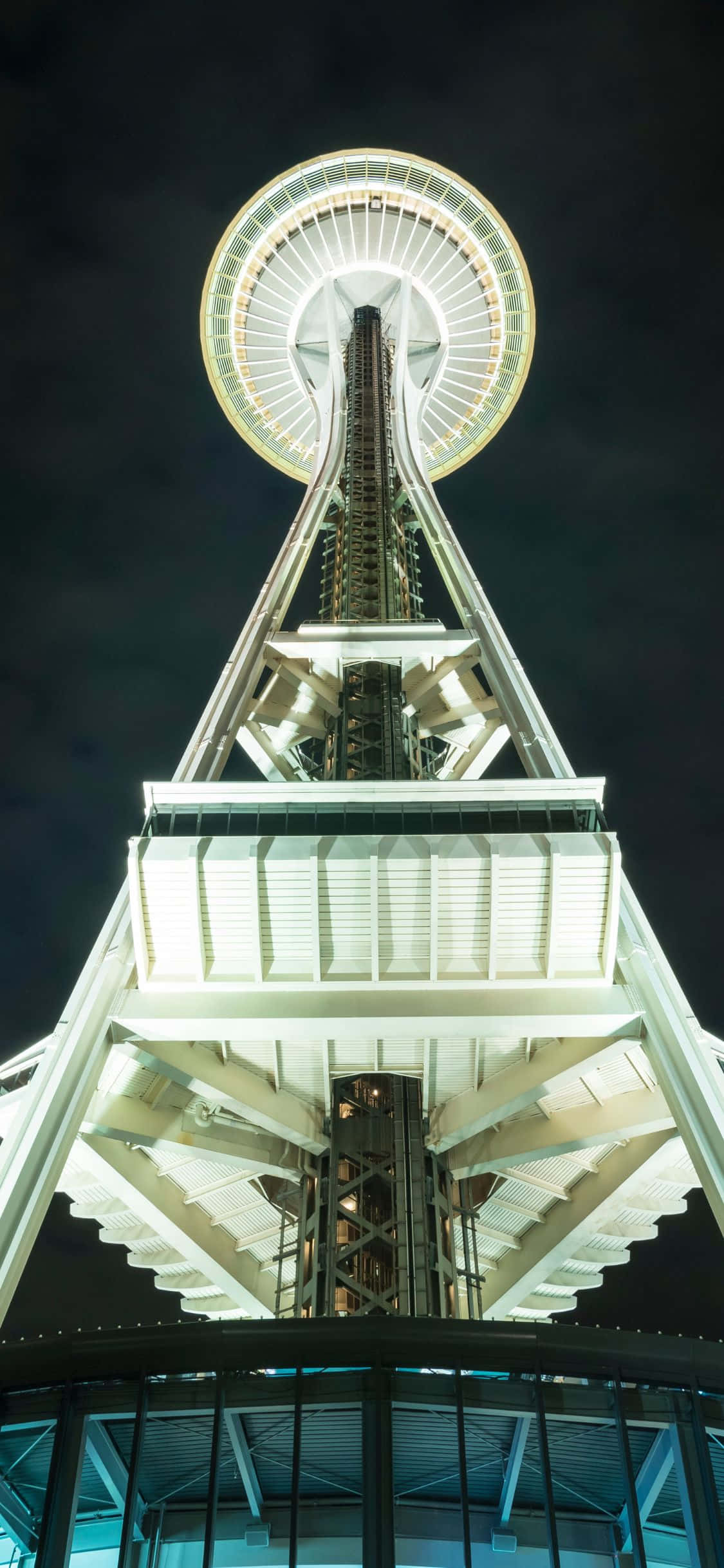 iPhone X Seattle 桌布 壁紙 — 西雅圖太空針塔在黑暗天空中發光的戲劇性低角度夜間照片。