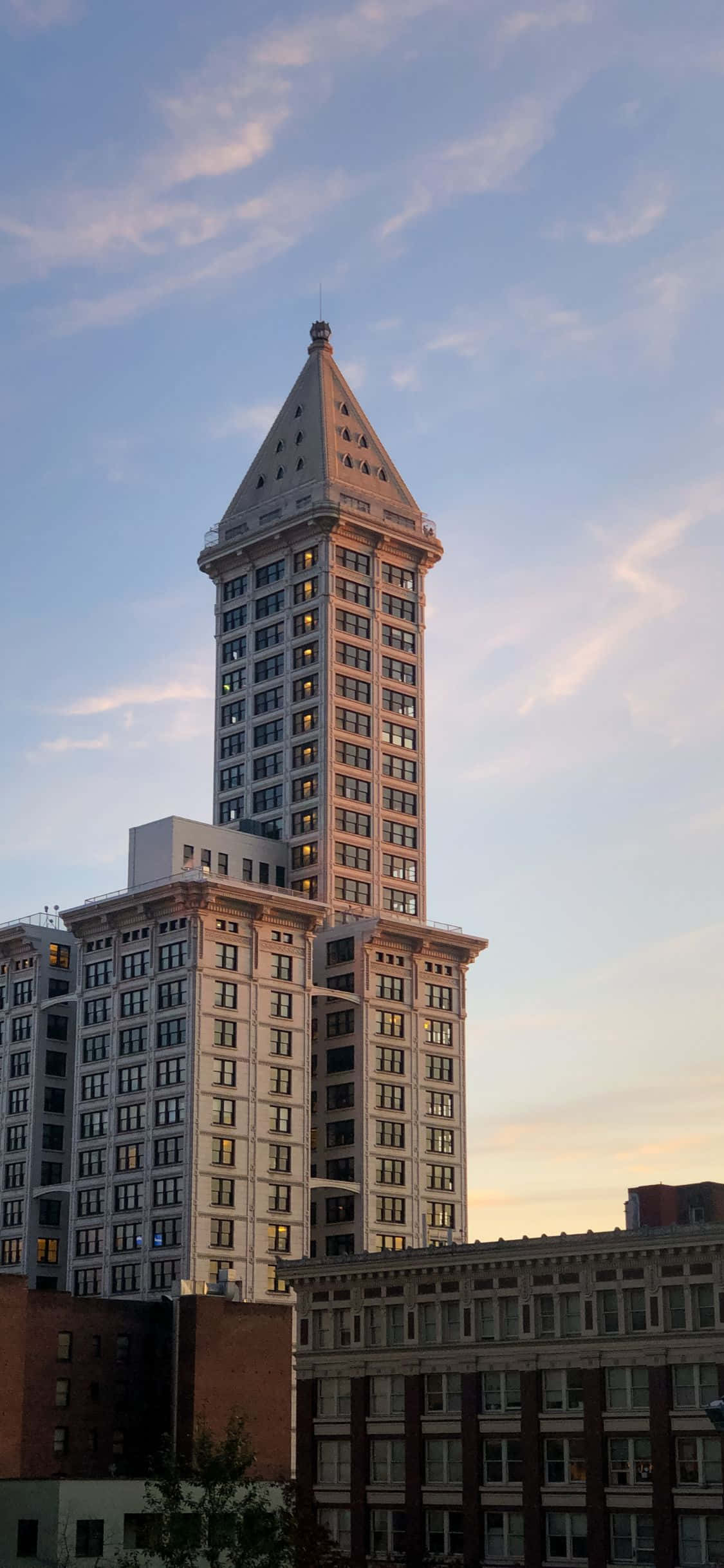 iPhone X Seattle 桌布 壁紙 — 西雅圖標誌性的史密斯塔在柔和的暮色天空中高聳，伴隨著縷縷雲彩和溫暖的金色光芒。