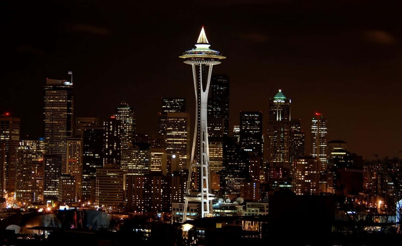 Washington 桌布 壁紙 — 西雅圖標誌性的太空針塔在漆黑的夜空中閃耀，周圍是廣闊的城市景觀，高樓大廈燈火通明。