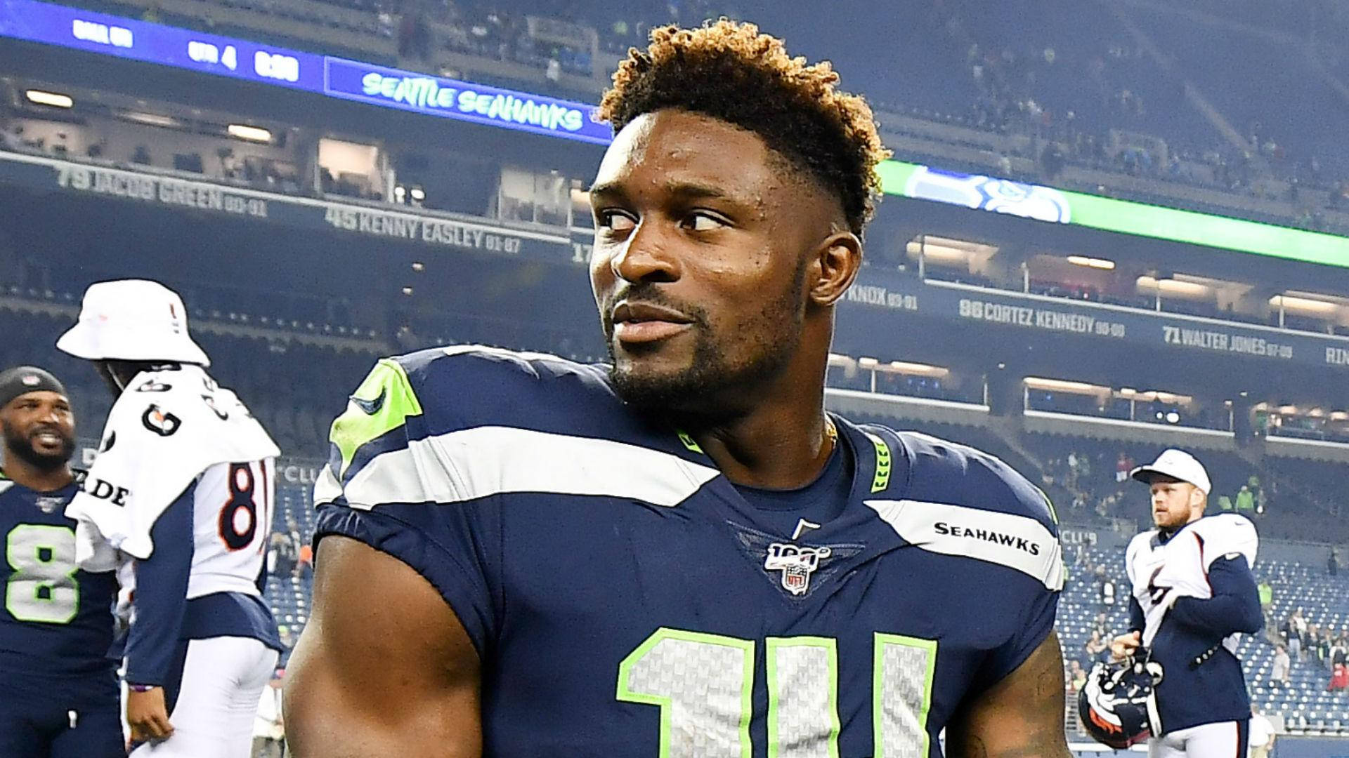 Dk 桌布 壁紙 — 西雅圖海鷹隊美式足球員11號在明亮的燈光下專注地站在球場上，隊友在附近。