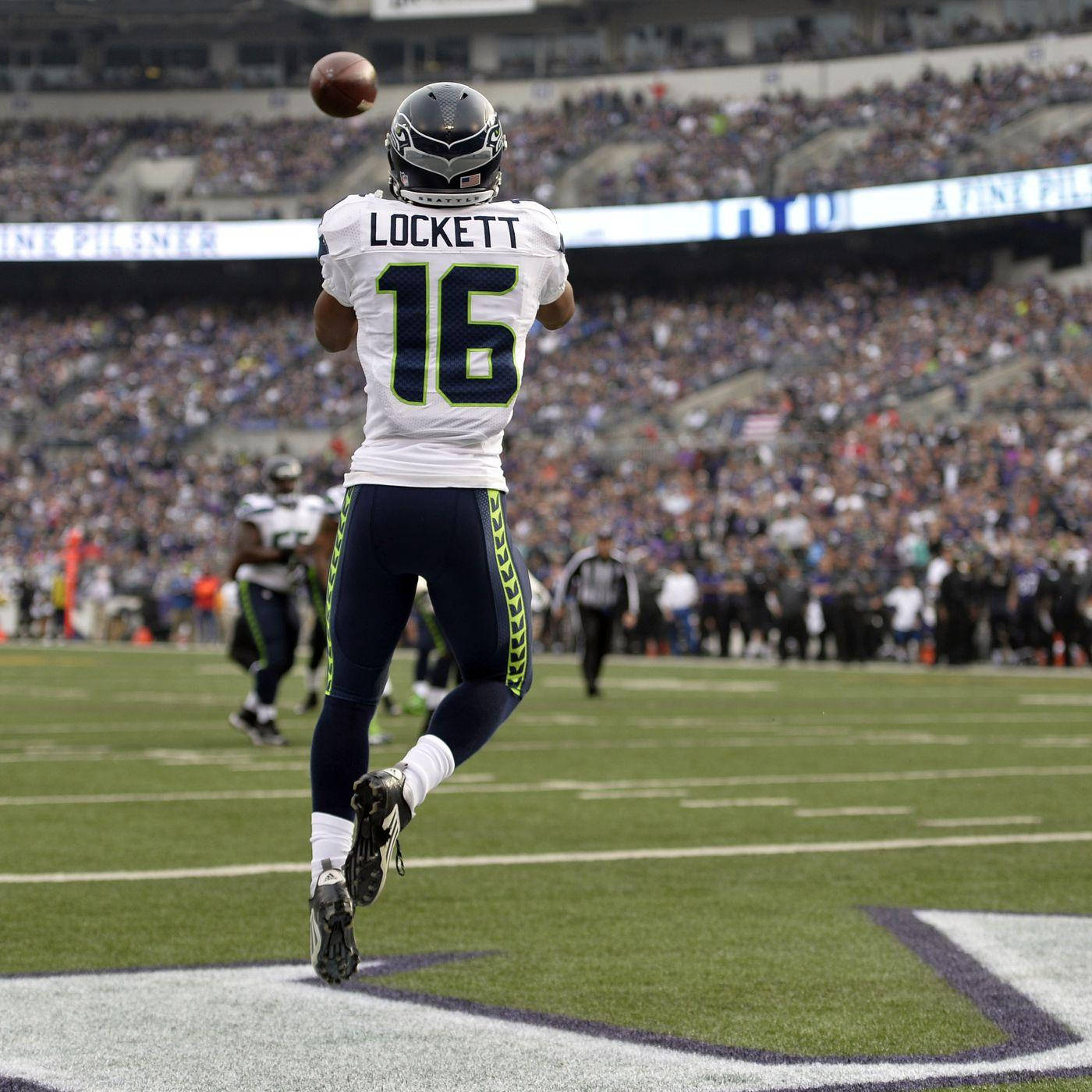 Seattle Seahawks 桌布 壁紙 — 西雅圖海鷹隊身穿白色16號球衣的球員在座無虛席的體育館比賽中跳起傳球。