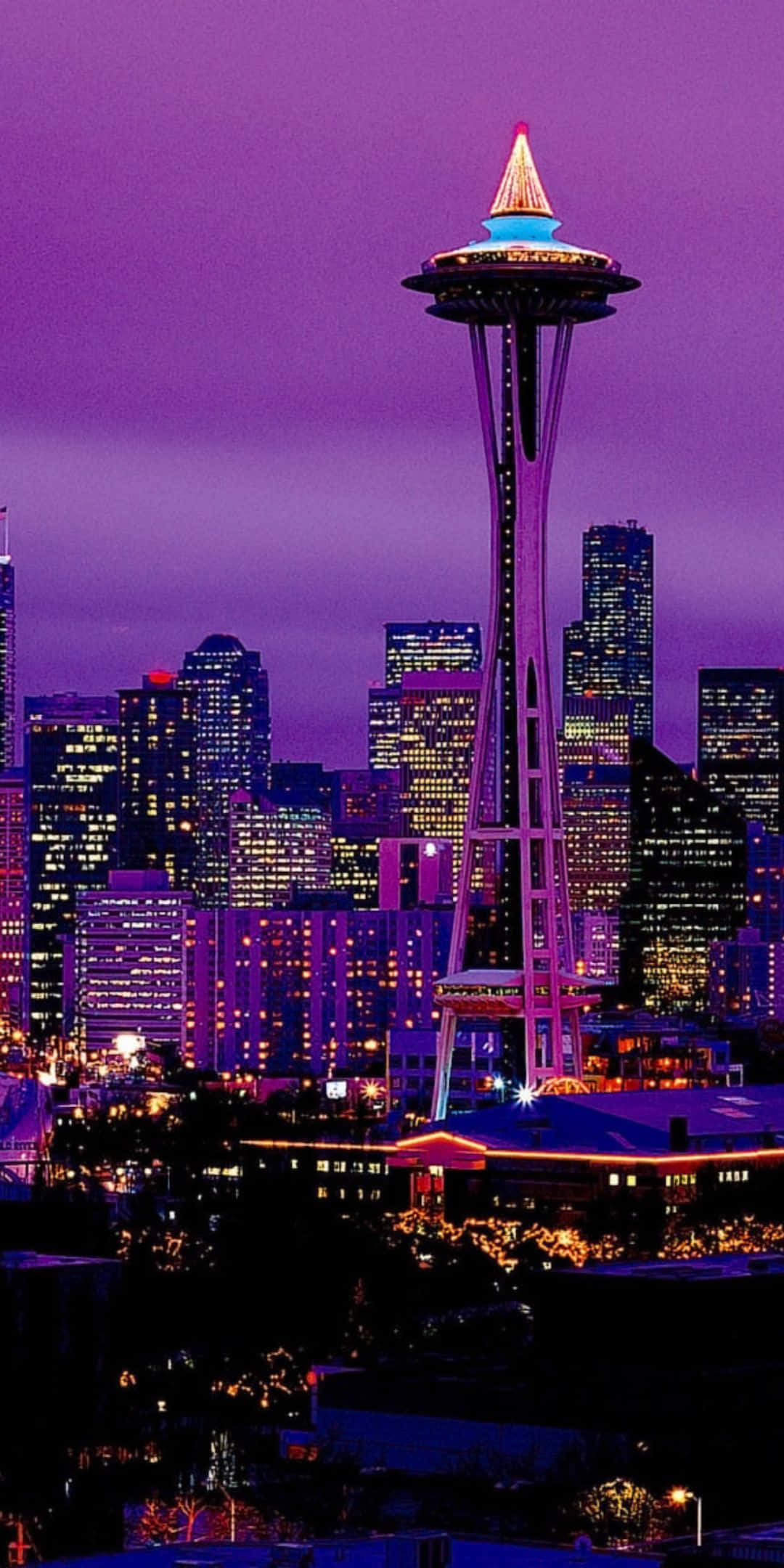 Pixel 3 Seattle 桌布 壁紙 — 西雅圖的太空針塔在深紫色暮色天空中閃耀，映襯著燈火通明的摩天大樓天際線。