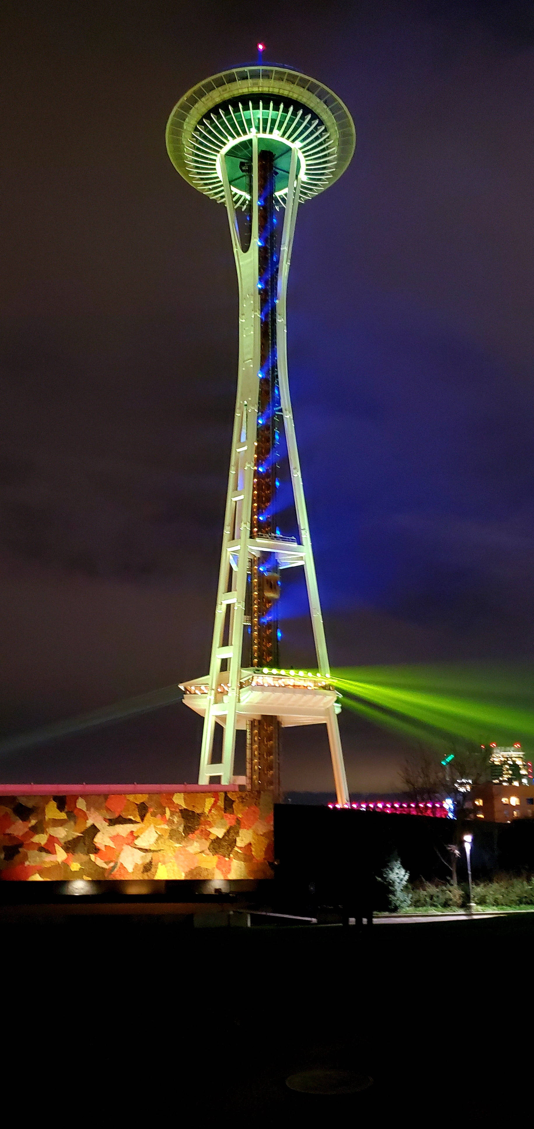 Space Needle 桌布 壁紙 — 西雅圖的太空針塔在漆黑的夜空中散發出鮮豔的綠色和藍色光芒，並有雷射光束向外射出。