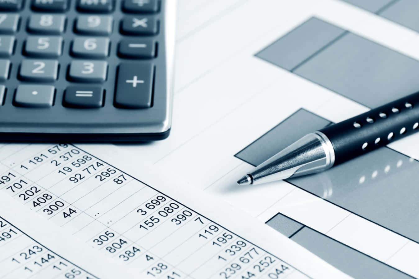 Budgeting 桌布 壁紙 — 計算機和筆的特寫，放在帶有條形圖和數值數據的財務試算表上。