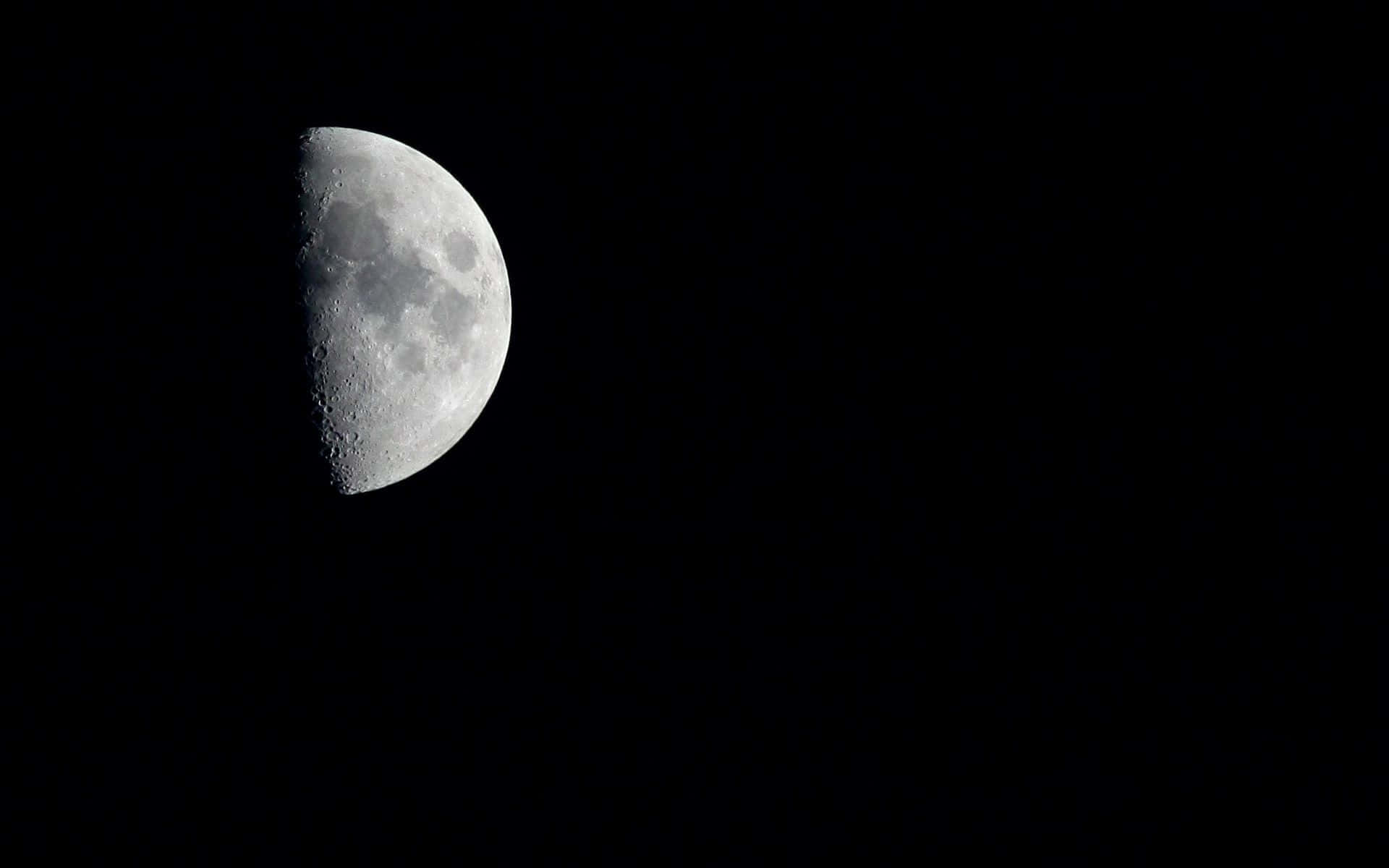 Half Moon 桌布 壁紙 — 詳細的半月亮在深黑色的夜空中發光，展示隕石坑和月球地形。