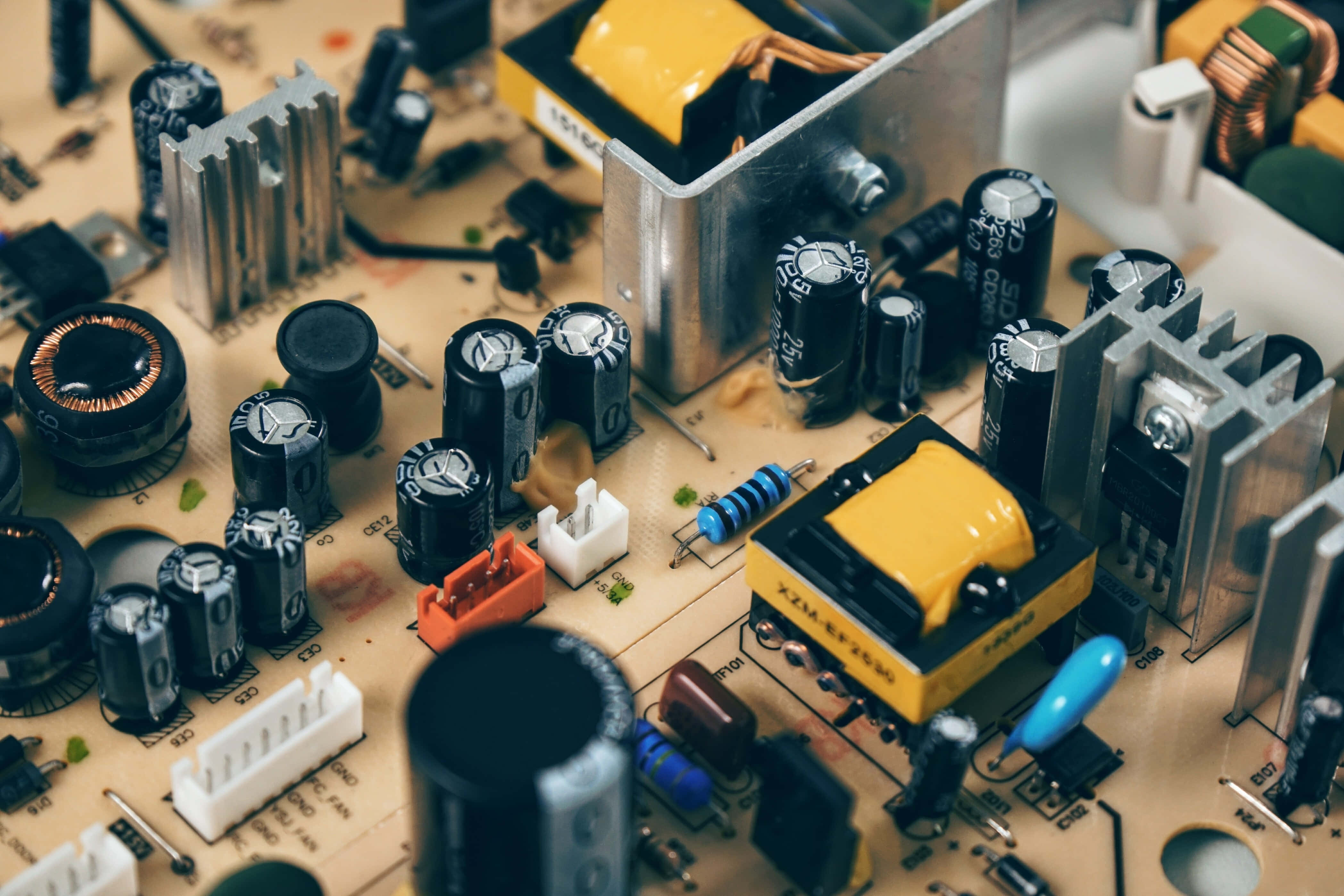 Electronics 桌布 壁紙 — 詳細電路板的特寫微距照片，帶有黑色電容器、黃色變壓器和金屬散熱器。