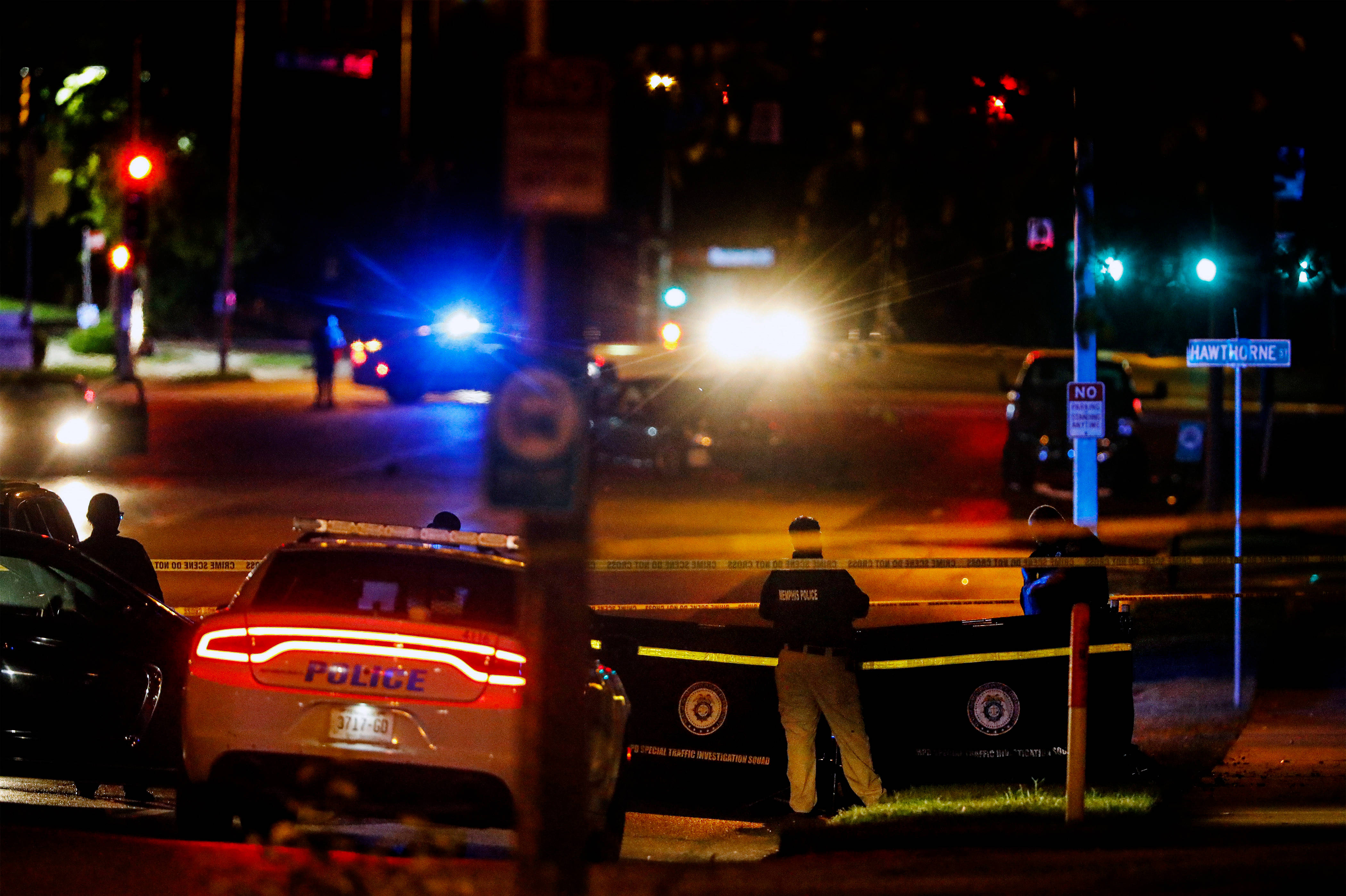 Road 桌布 壁紙 — 警車閃著警燈，在夜晚的街燈和交通號誌下包圍著犯罪現場。