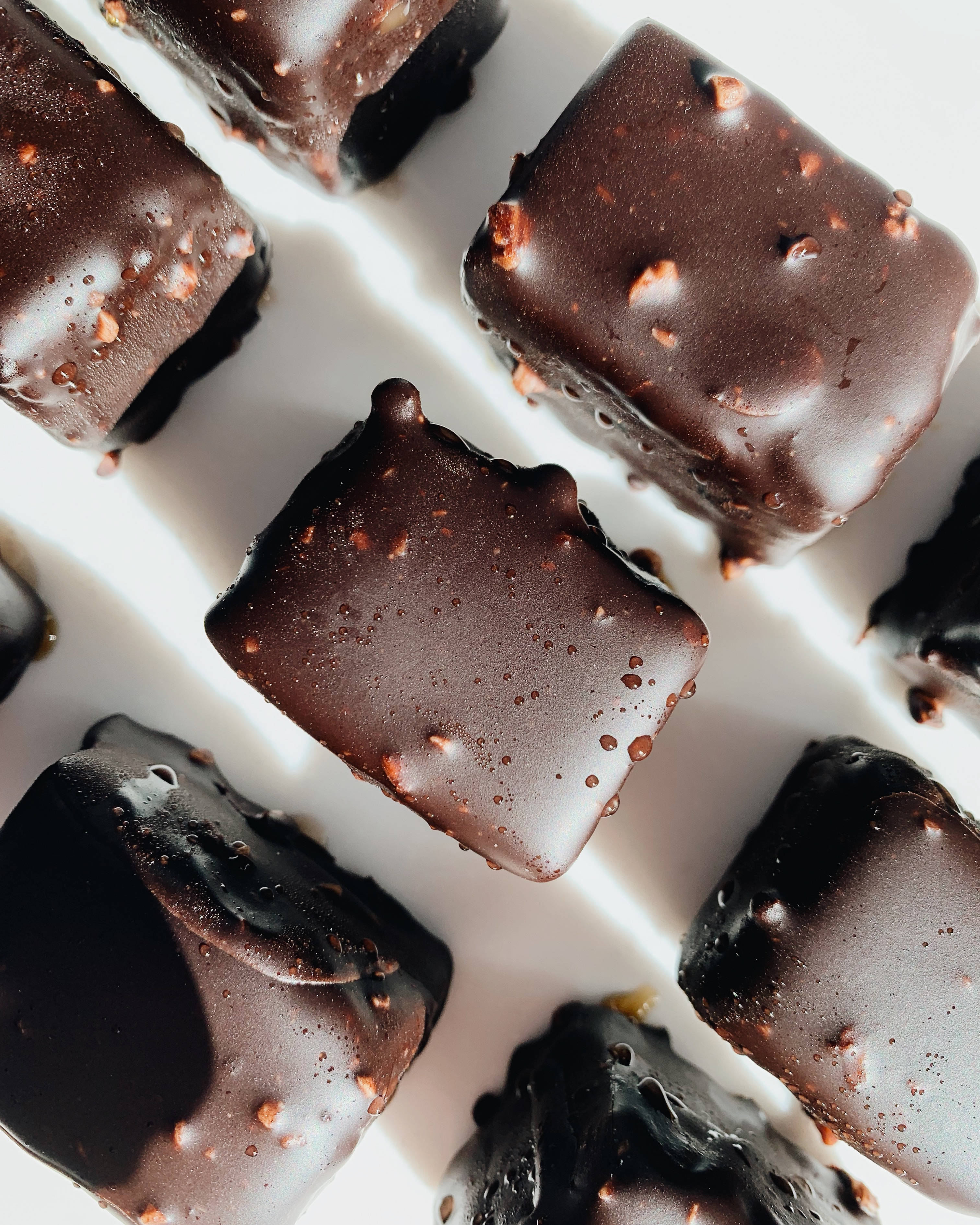 Chocolate 桌布 壁紙 — 豐富光澤的巧克力方塊，撒上碎堅果，排列在明亮的白色表面上。