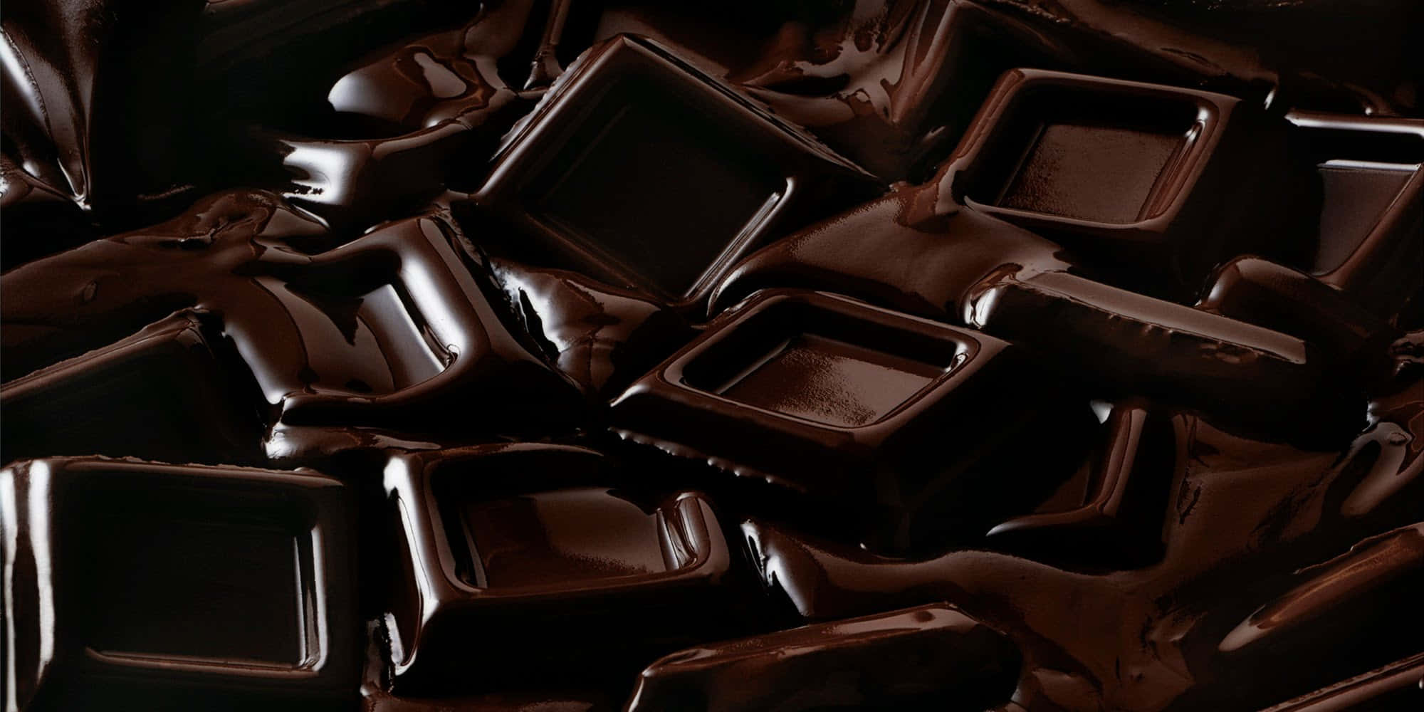 Dark Chocolate 桌布 壁紙 — 豐富光澤的深黑巧克力方塊在奢華的特寫中融化在一起，帶有深棕色亮點。