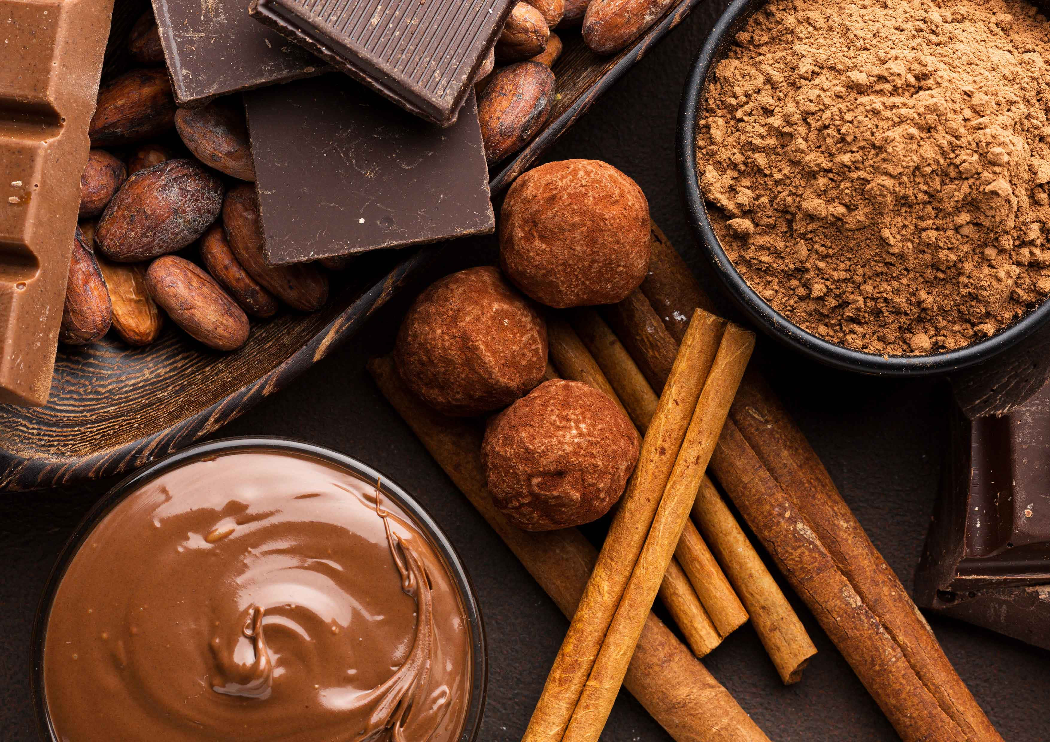 Chocolate 桌布 壁紙 — 豐富的巧克力松露、肉桂棒、可可粉和巧克力棒以頹廢的俯視食物構圖排列。