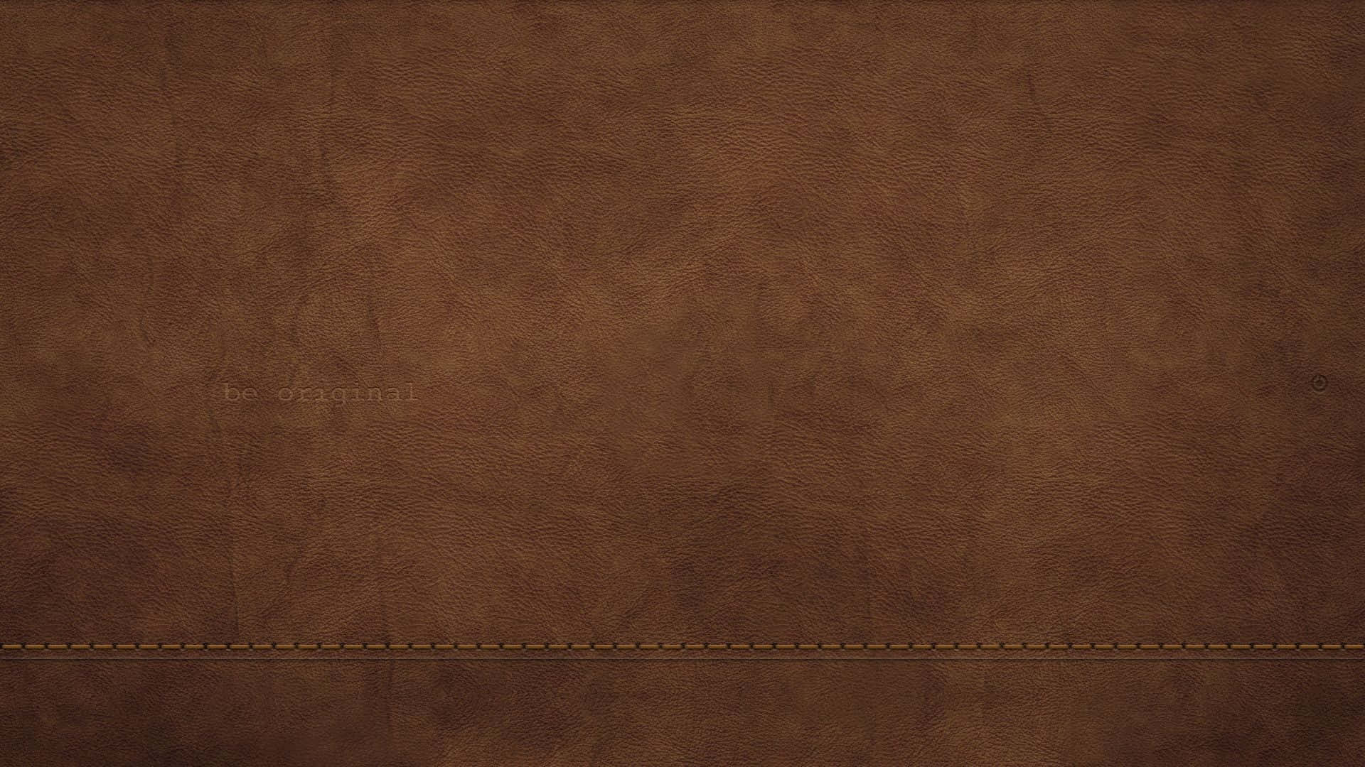 Brown Leather 桌布 壁紙 — 豐富的棕色皮革質感，表面帶有細微縫線和模糊壓印文字。