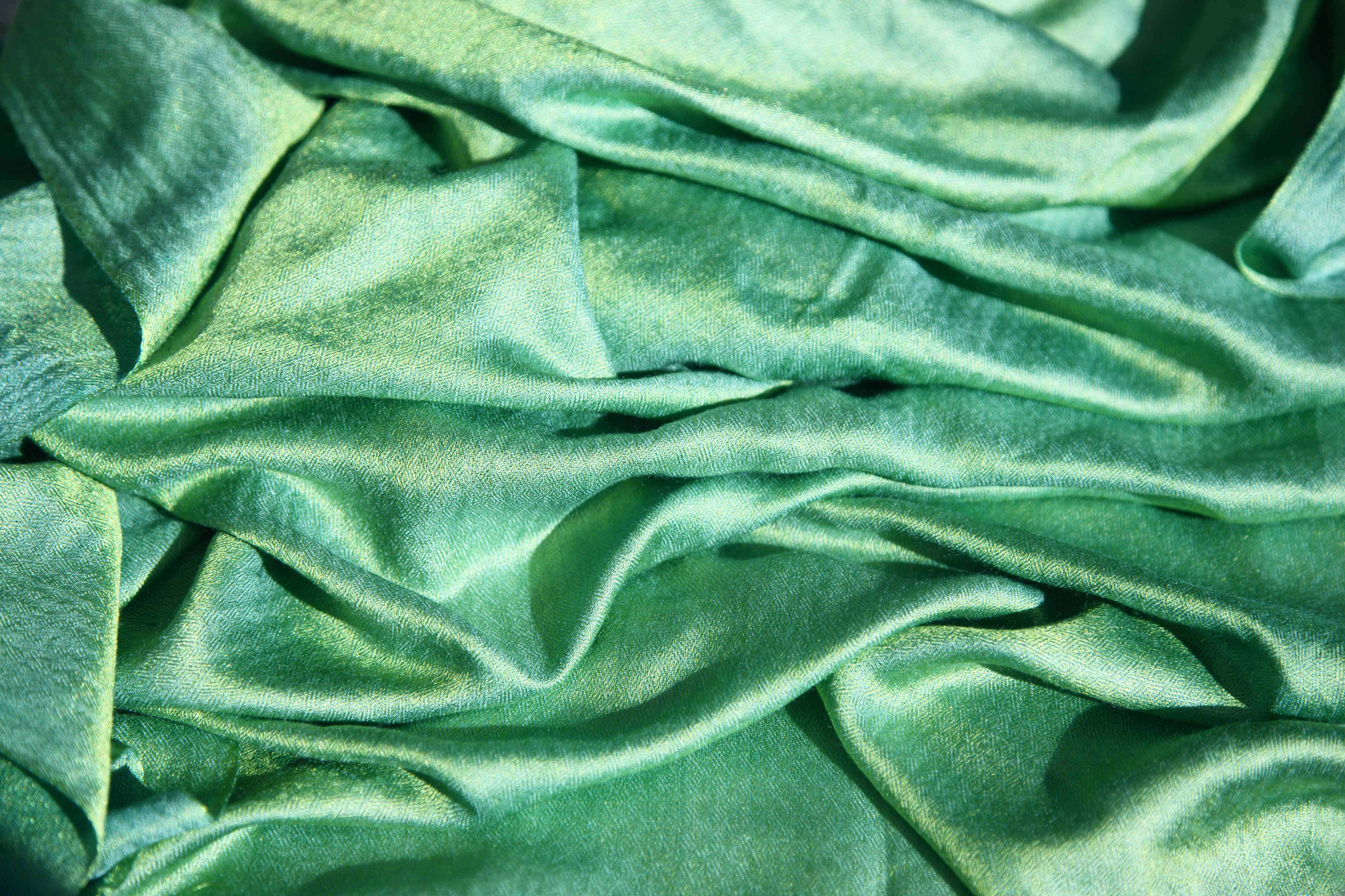 Green Texture 桌布 壁紙 — 豐富的祖母綠絲綢布料，光澤褶皺在特寫紋理鏡頭中捕捉柔和光線。