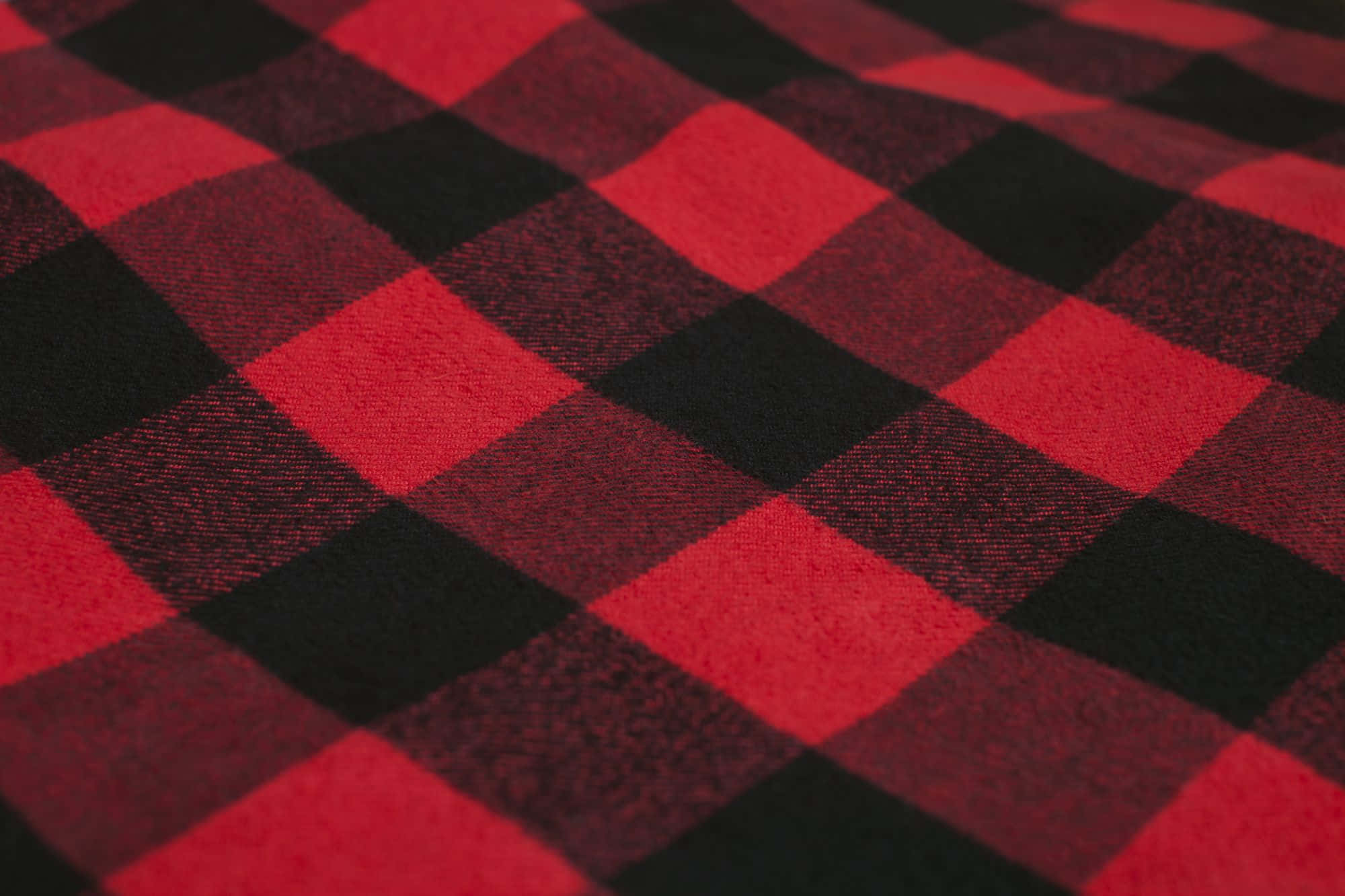 Plaid 桌布 壁紙 — 豐富的紅黑 buffalo 格紋布料特寫，可見編織紋理及柔和光線。