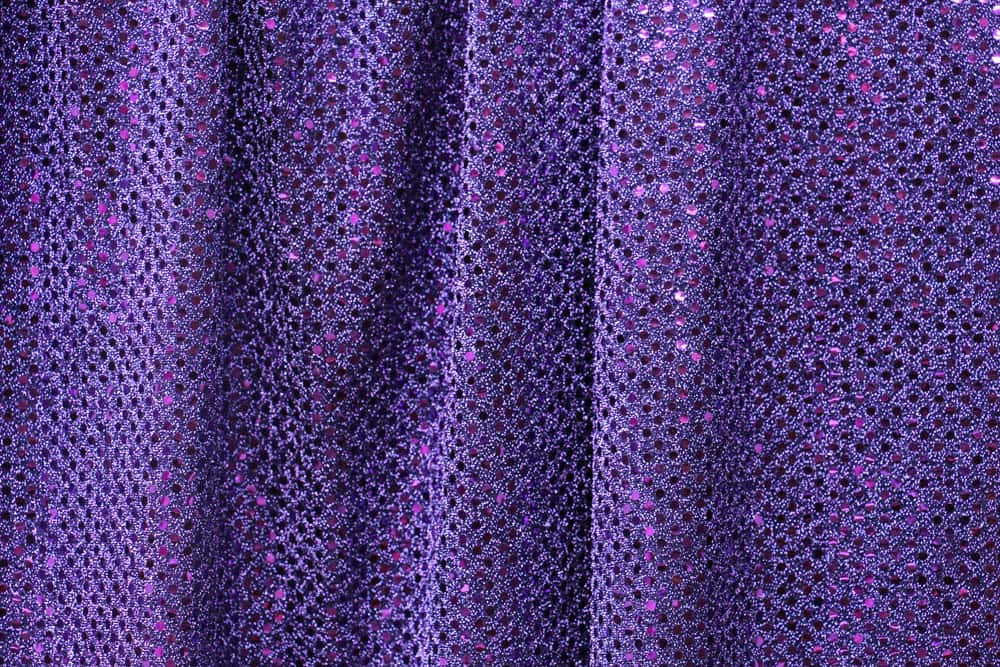 Purple Sequins 桌布 壁紙 — 豐富的紫色布料，帶有閃閃發光的亮片和紋理褶皺，在閃爍的特寫中捕捉光線。