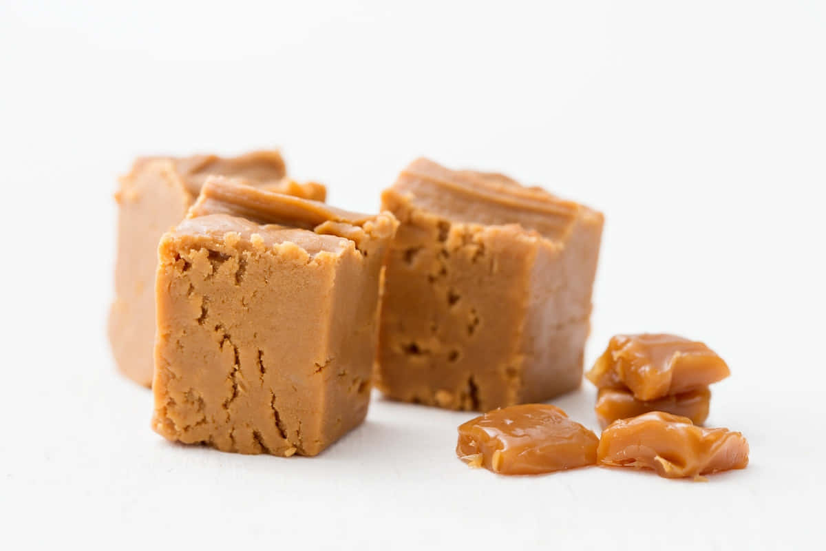 Penuche Fudge 桌布 壁紙 — 豐富的金黃色焦糖軟糖方塊和碎塊在純白背景上閃閃發光。