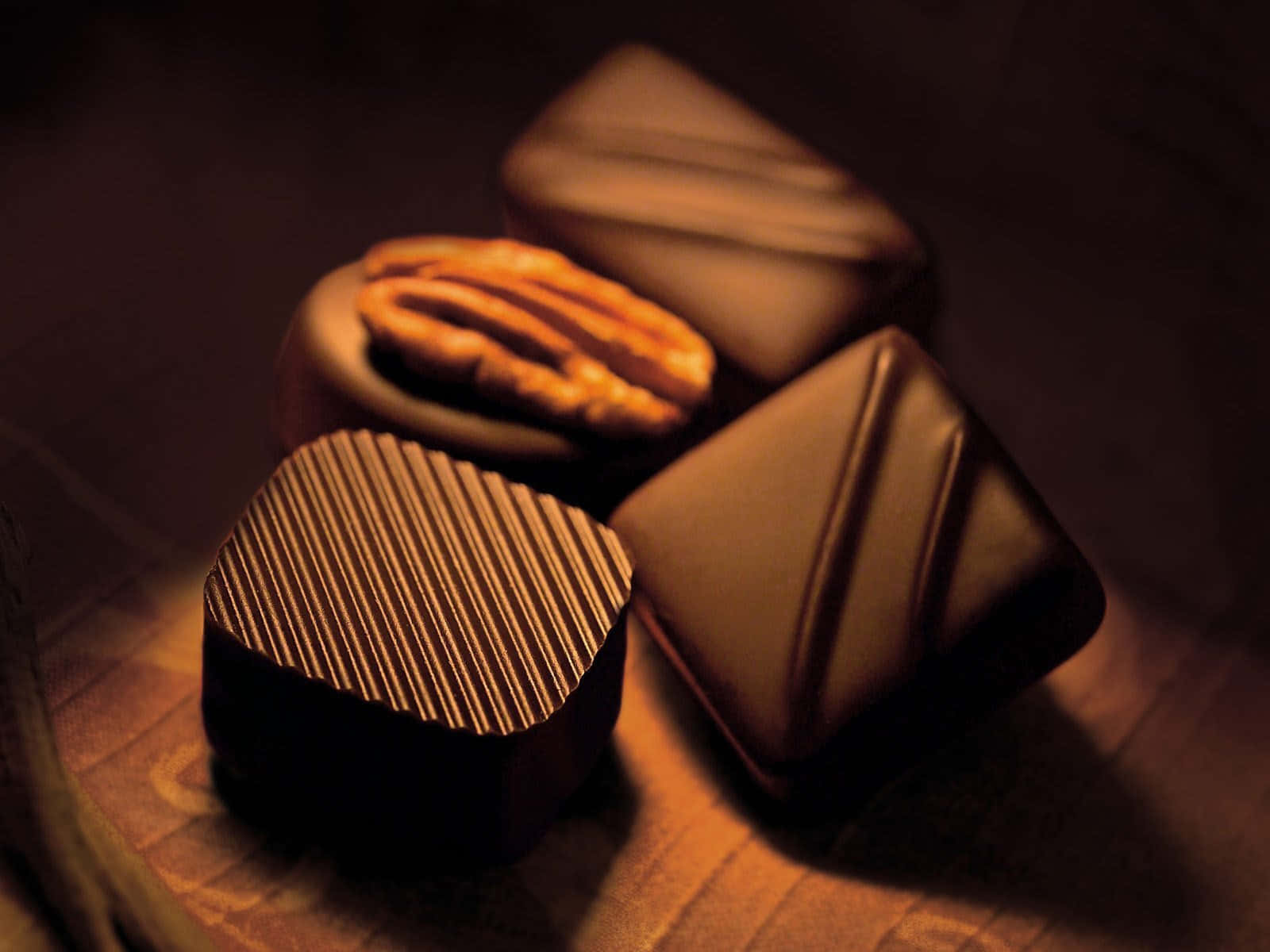 Dark Chocolate 桌布 壁紙 — 豐富的黑巧克力，帶有紋理和堅果填充的設計，溫暖地照亮在木質表面上。