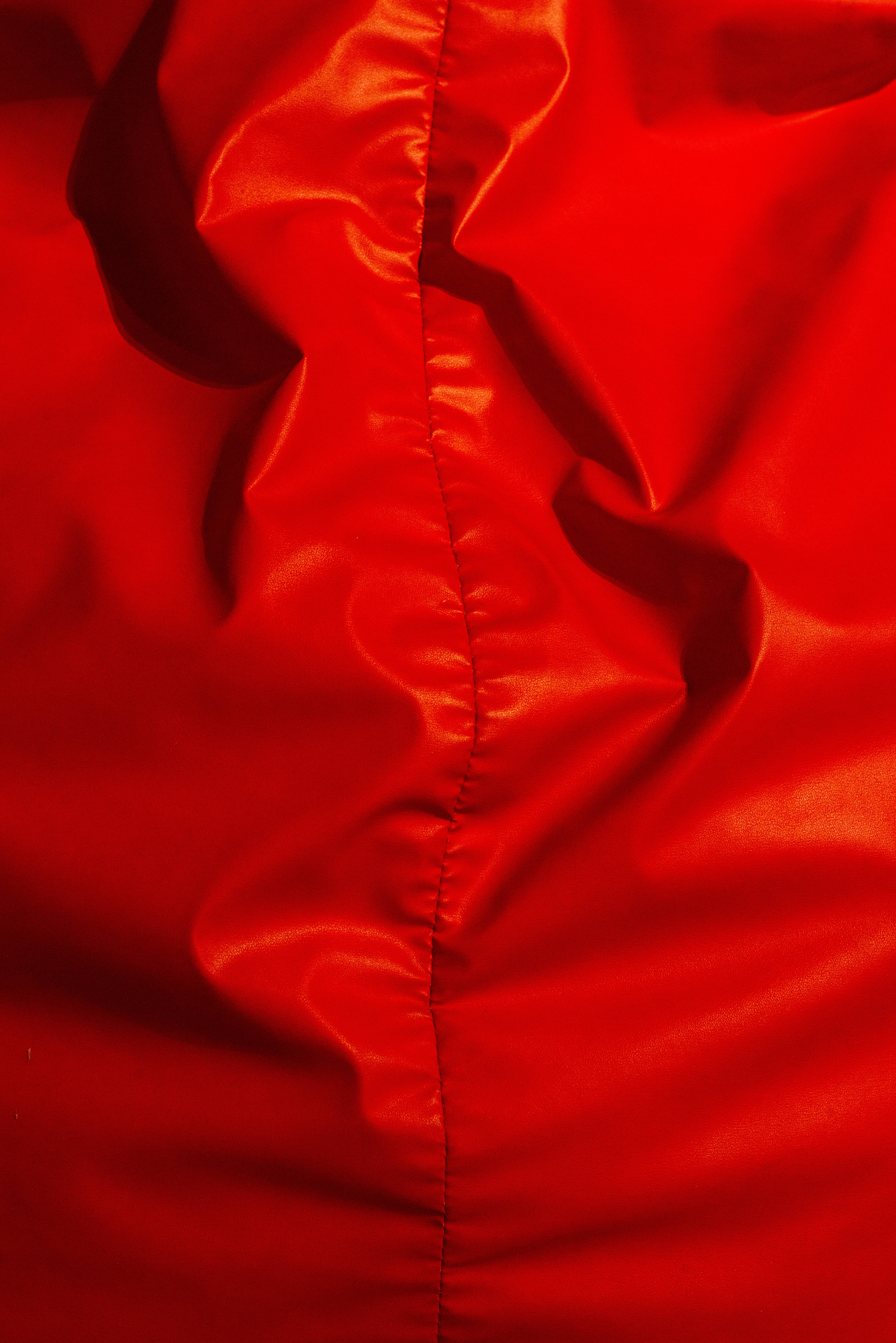 Stitch 桌布 壁紙 — 豐富紅色緞面布料特寫，帶有光澤褶皺和中央縫線，捕捉柔和光線。