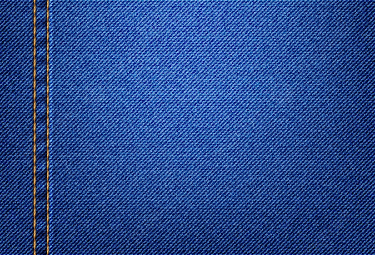 Denim 桌布 壁紙 — 豐富藍色牛仔布料的特寫，左側有一條垂直的黃色縫線。