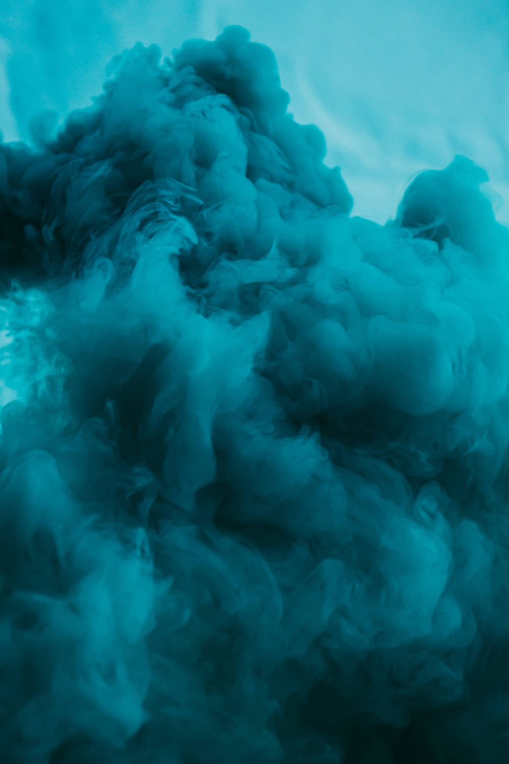 Blue Smoke 桌布 壁紙 — 豐盈的藍綠色墨水漩渦在柔和的漸變背景上翻騰擴散，營造出夢幻般的抽象構圖。