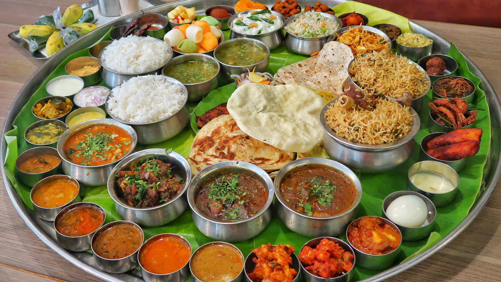 Indian 桌布 壁紙 — 豐盛的印度塔利，包括米飯、豆泥、咖哩、印度烤餅和酸辣醬，排列在香蕉葉上的金屬碗中。