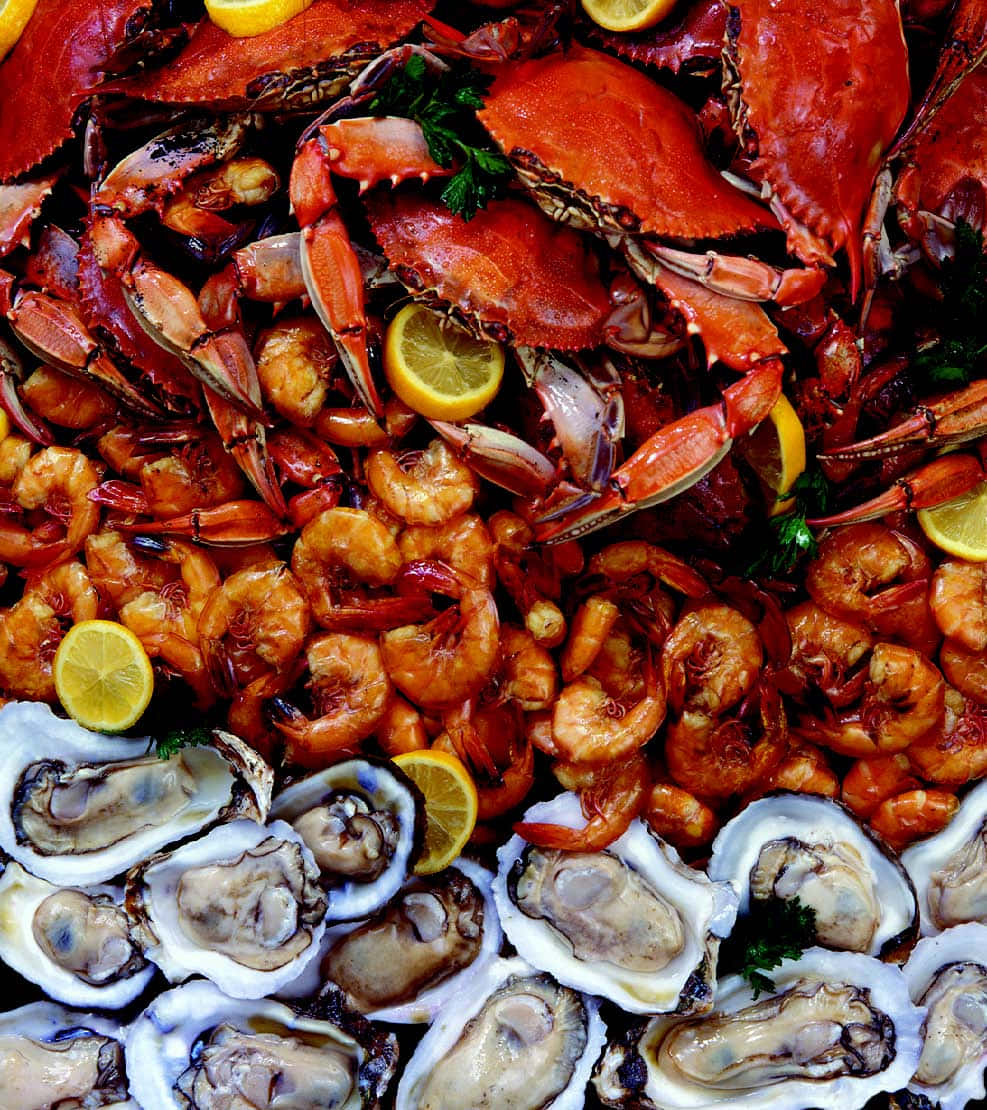 Seafood 桌布 壁紙 — 豐盛的海鮮拼盤，包括鮮紅色的螃蟹、多汁的蝦和新鮮的牡蠣，配以檸檬片和歐芹裝飾。
