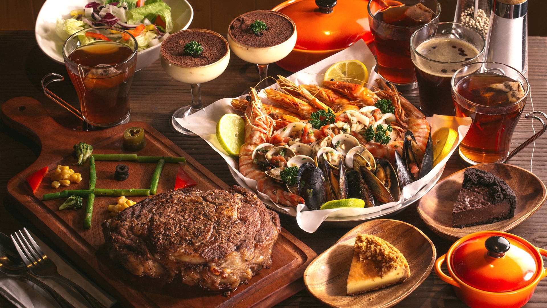 Seafood 桌布 壁紙 — 豐盛的美食拼盤，包括煎牛排、海鮮、蛤蜊和甜點，擺放在質樸的木桌上。