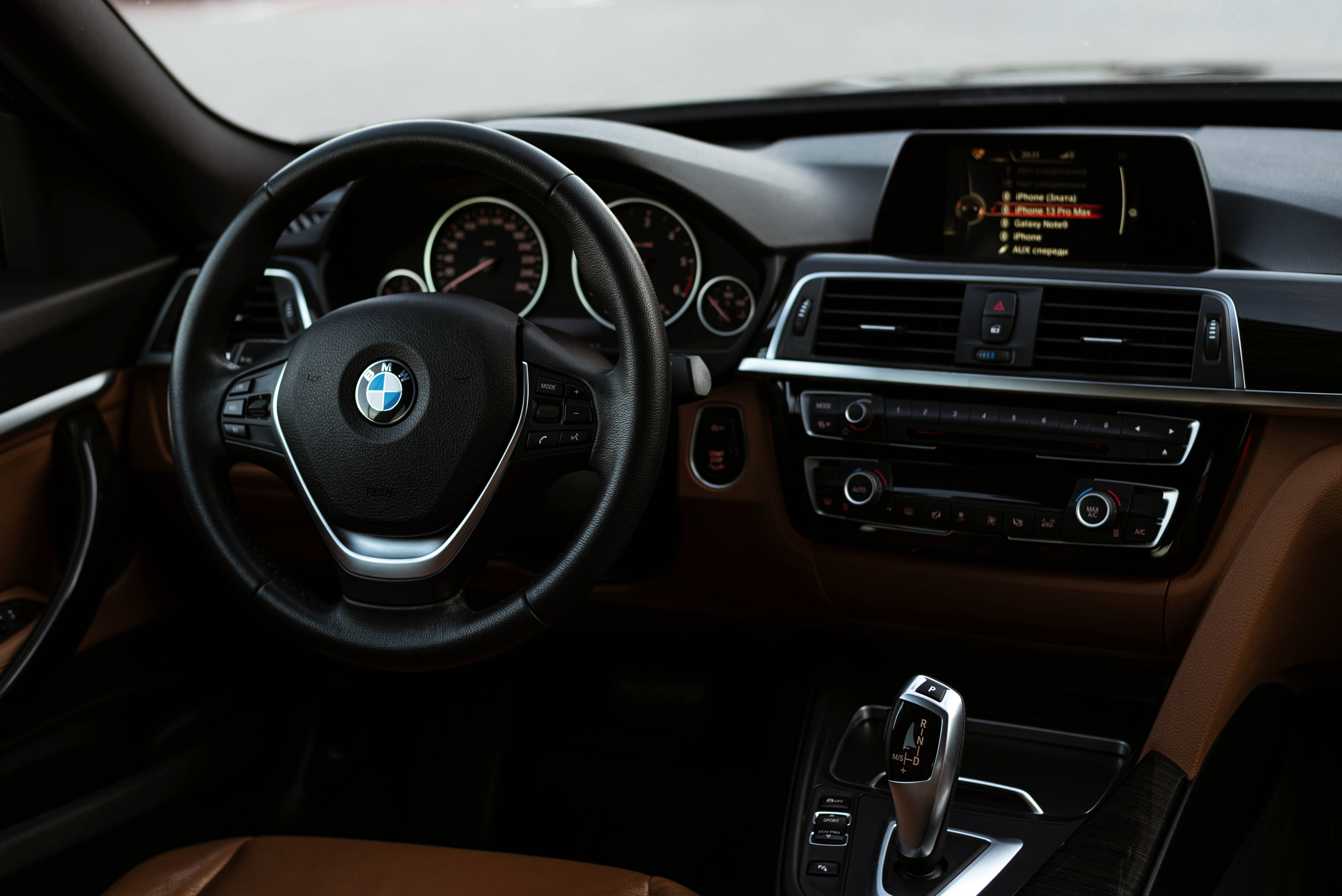 Black Bmw 桌布 壁紙 — 豪華BMW汽車內飾，配備黑色皮革方向盤和棕褐色皮革座椅，柔和環境照明。